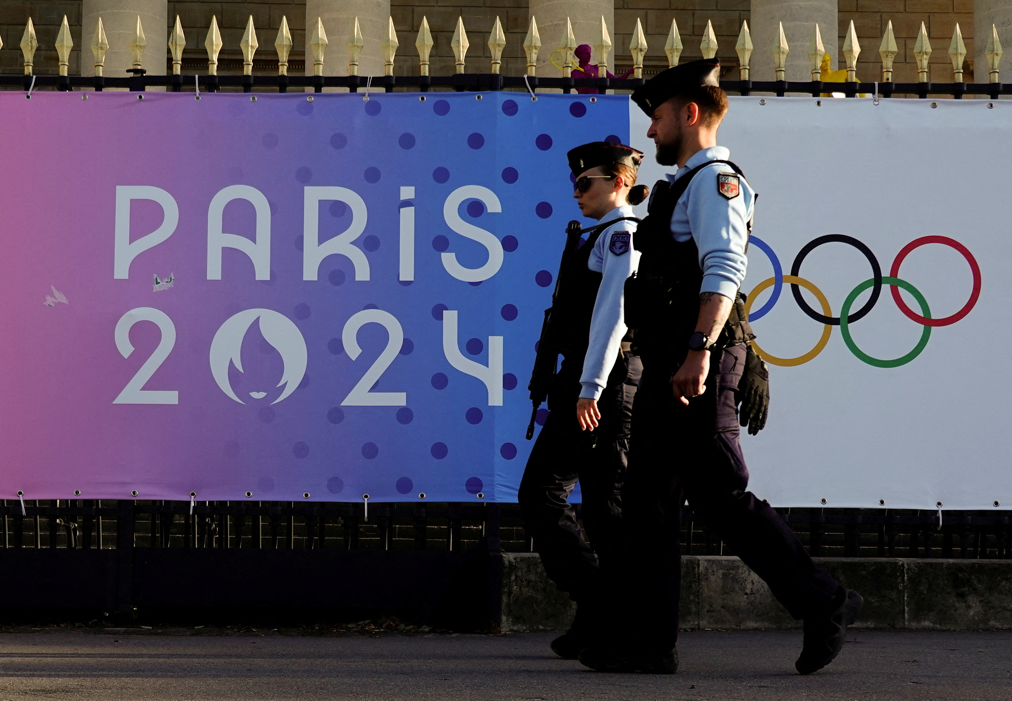 French gendarmes patrol a street near a poster advertising the Paris 2024 Summer Games in Paris