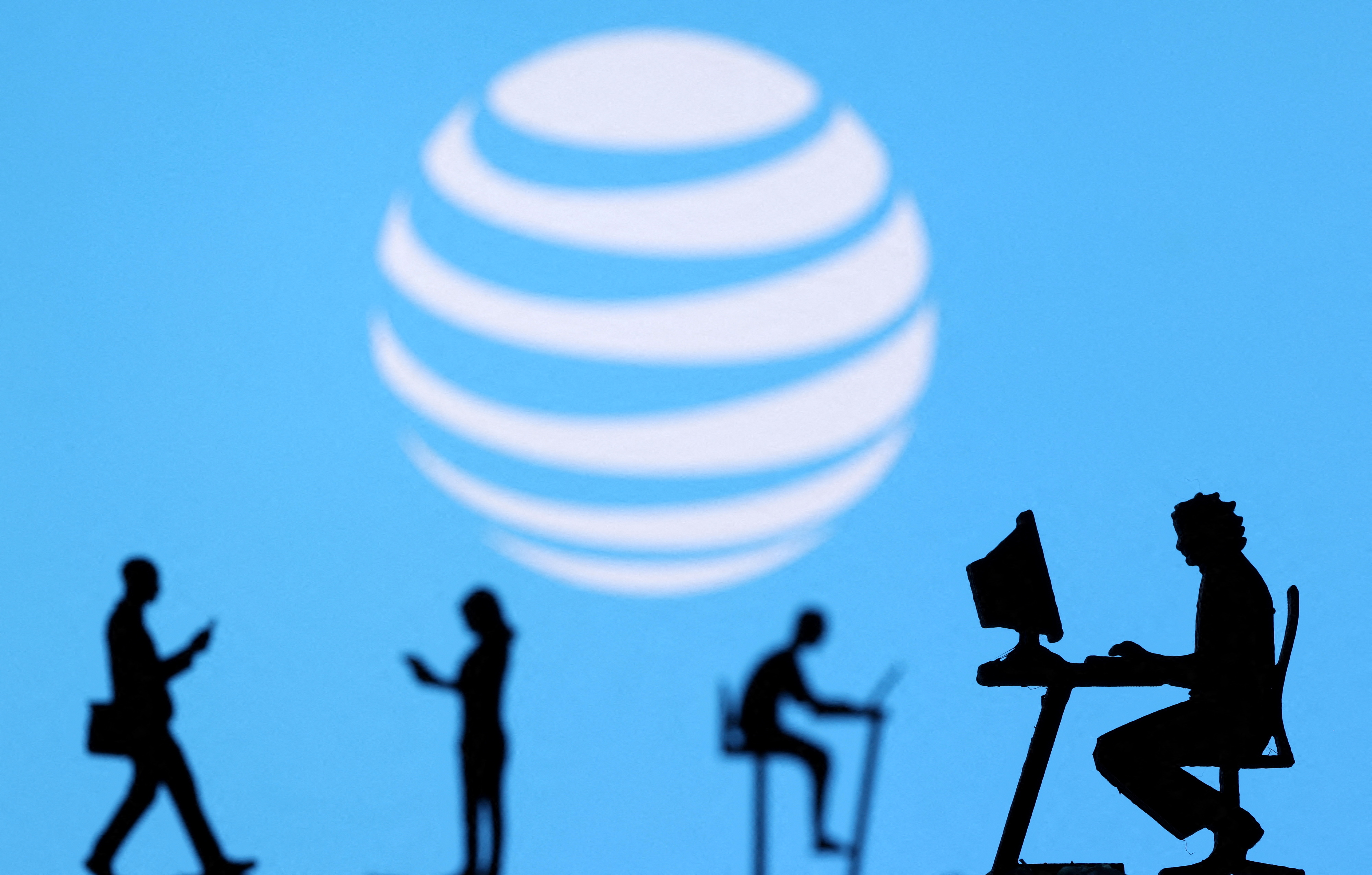 Small toy figures with laptops and smartphones are seen in front of displayed AT&T logo, in this illustration taken December 5, 2021. REUTERS/Dado Ruvic/Illustration/File Photo