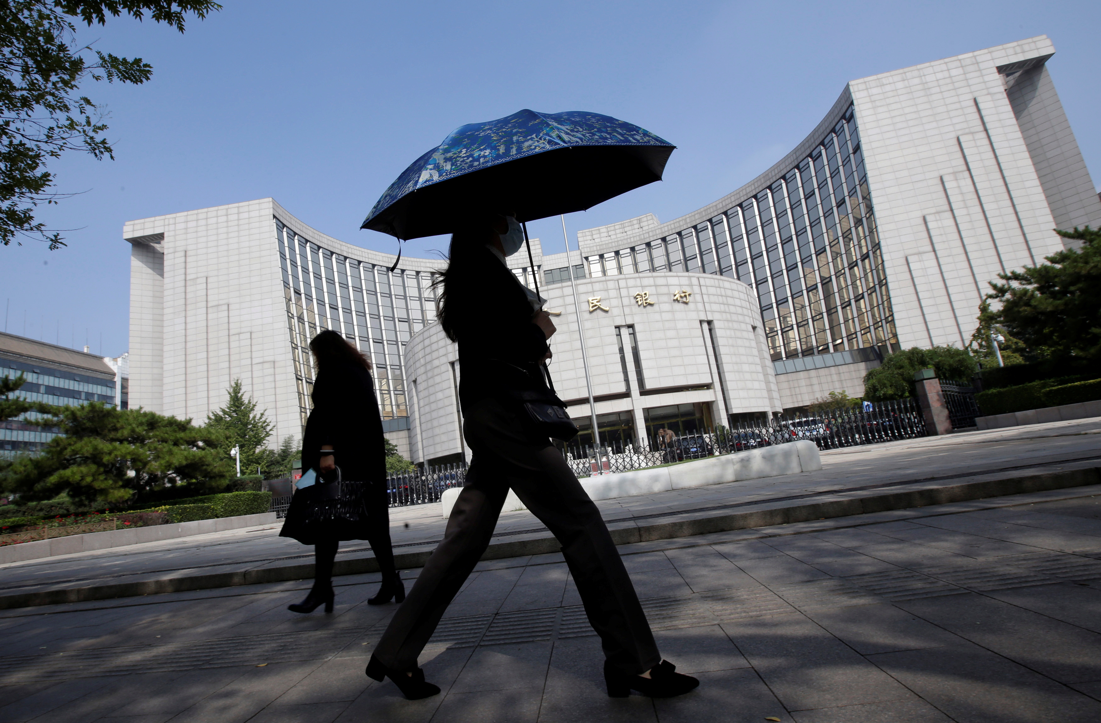 People walk past the headquarters of the PBOC, the central bank, in Beijing