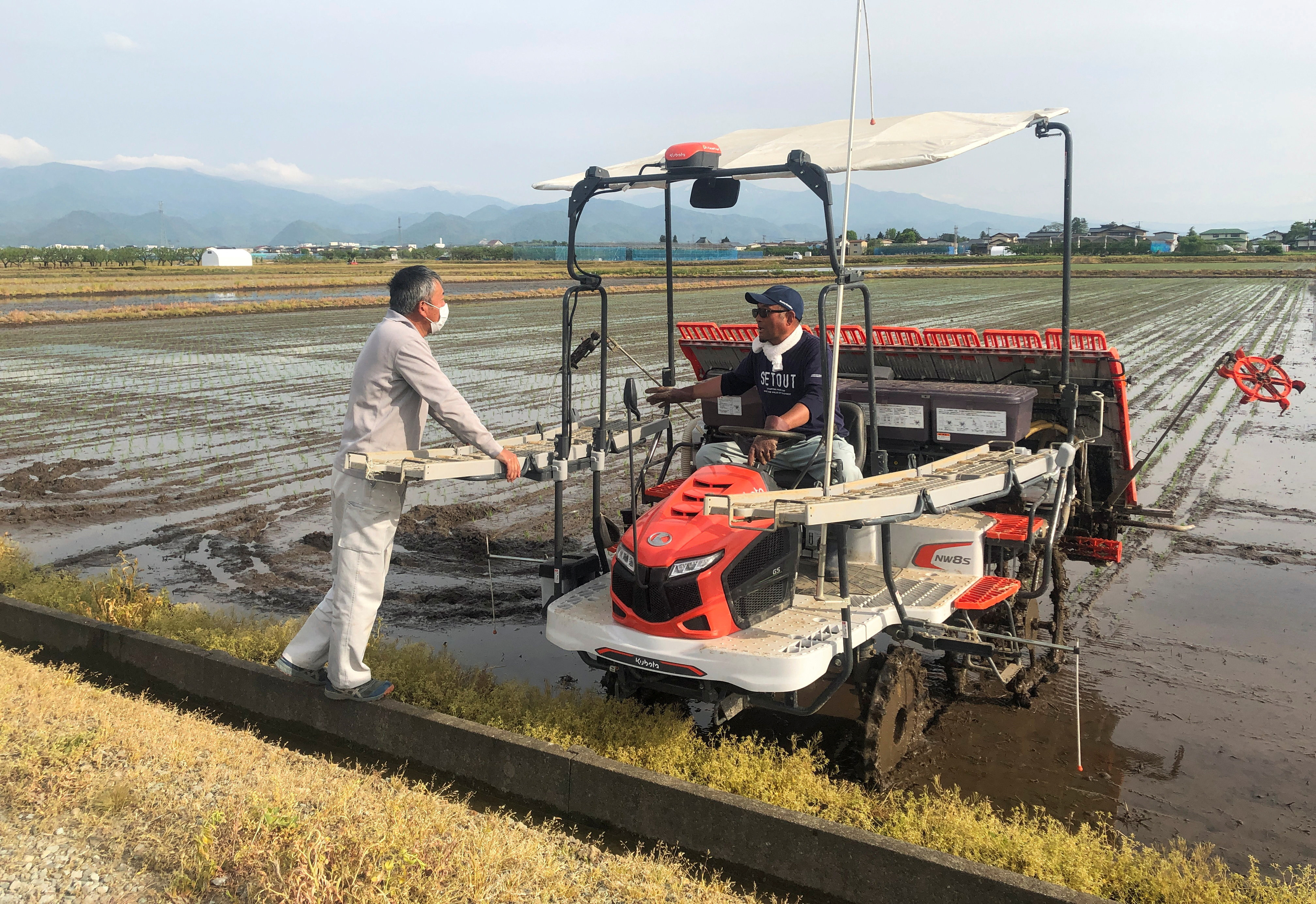 Rice farmer Kazuyuki Oshino chats with his son-in-law at a rice field, in Tendo