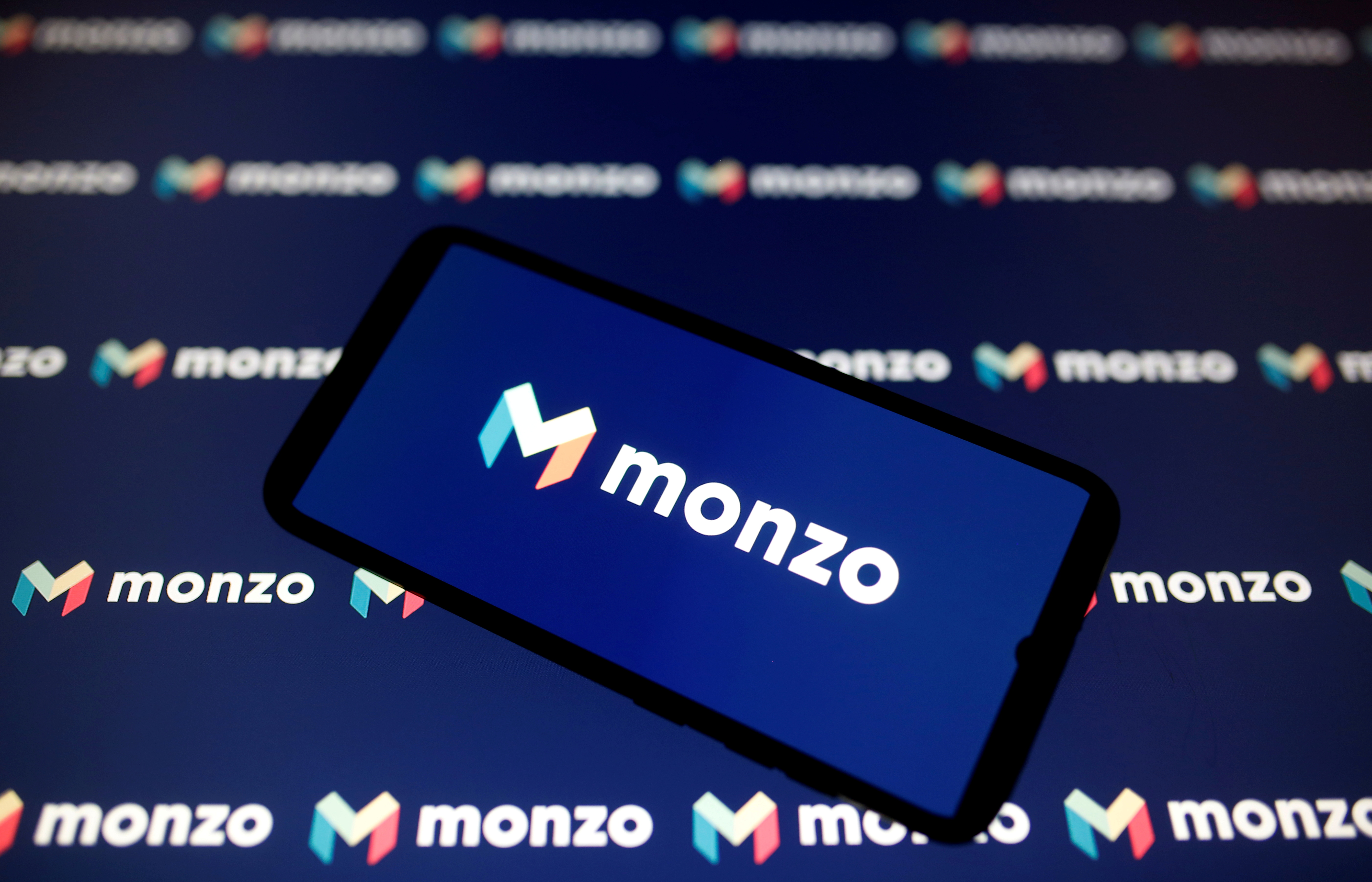 A smartphone displays a Monzo logo in this illustration