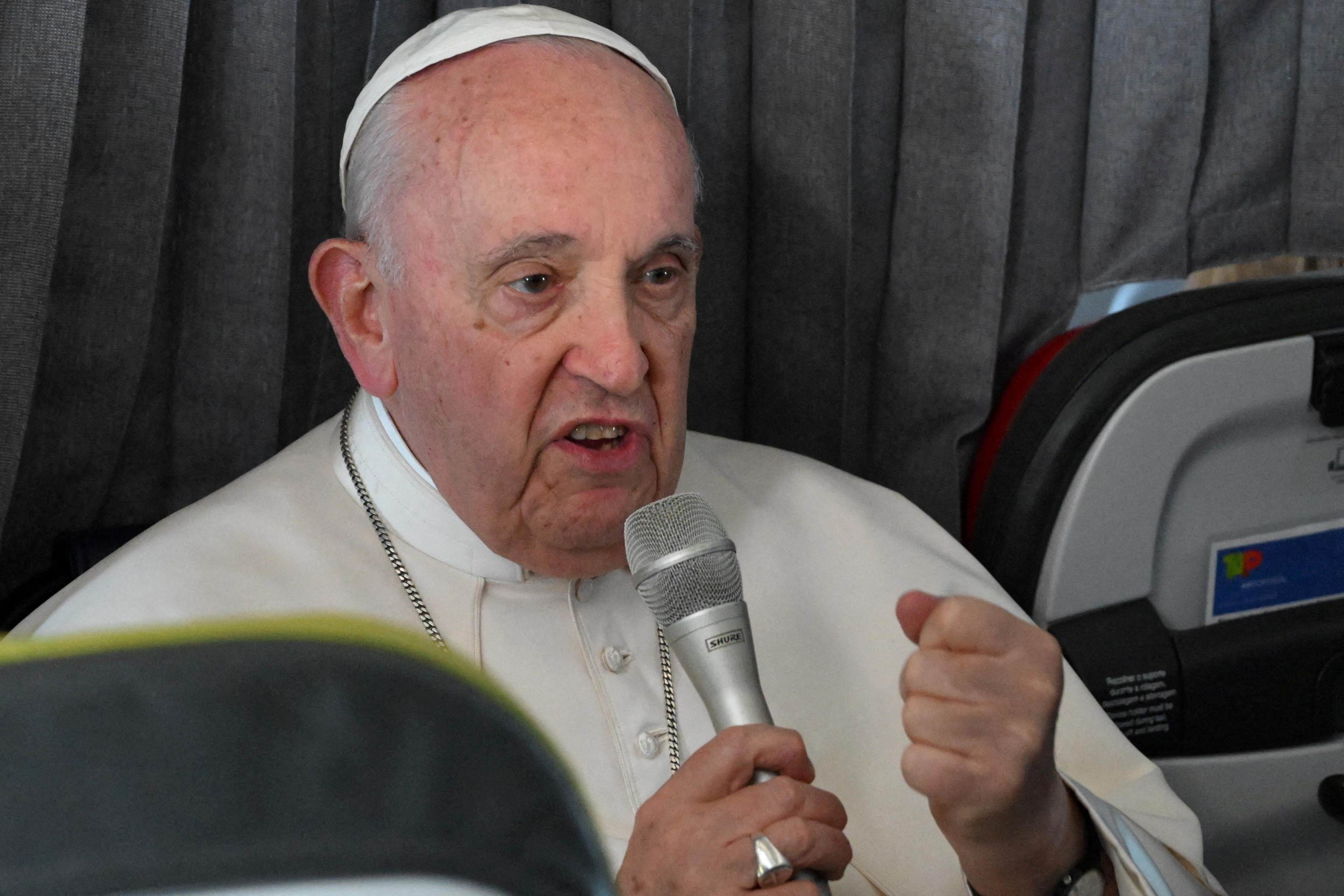 Pope Francis attends a press conference onboard a plane en route to Rome