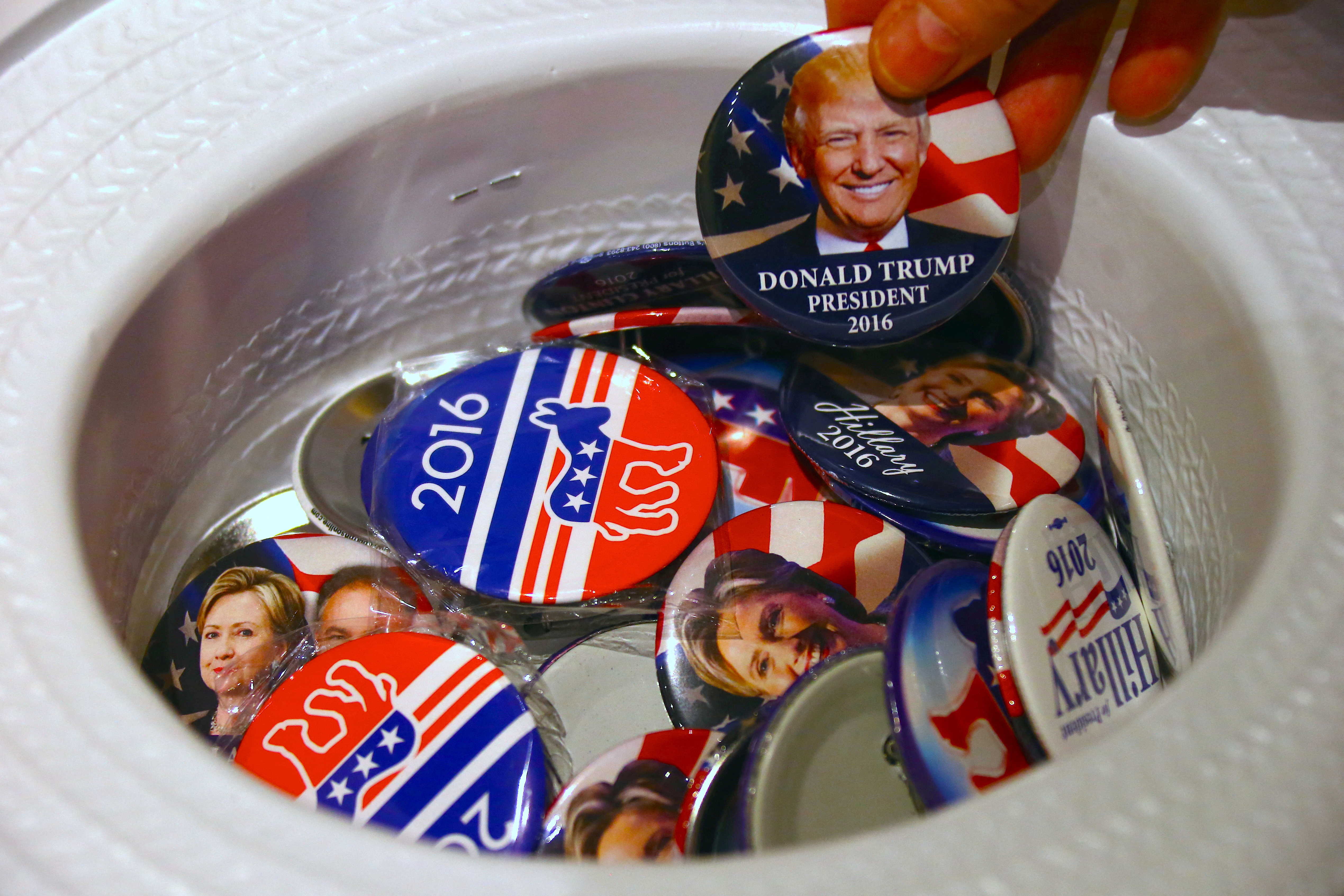 A guest at an event called the U.S. Presidential Election Watch, organised by the U.S. Consulate, reaches for a badge from out of a hat displaying photographs of Republican candidate Donald Trump and Democratic candidate Hillary Clinton, in Syd