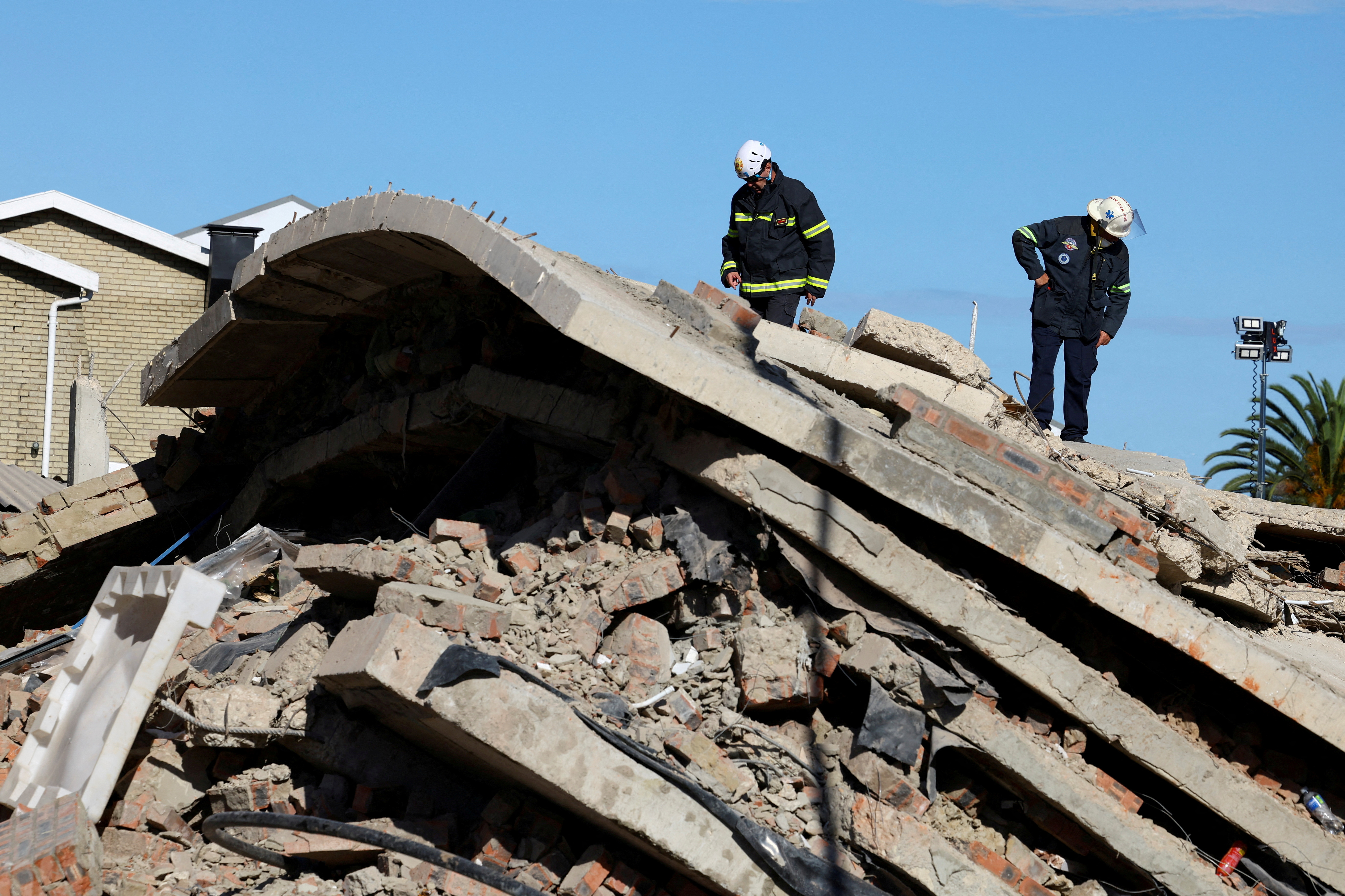 Rescuers work to rescue construction workers trapped under a building that collapsed in George