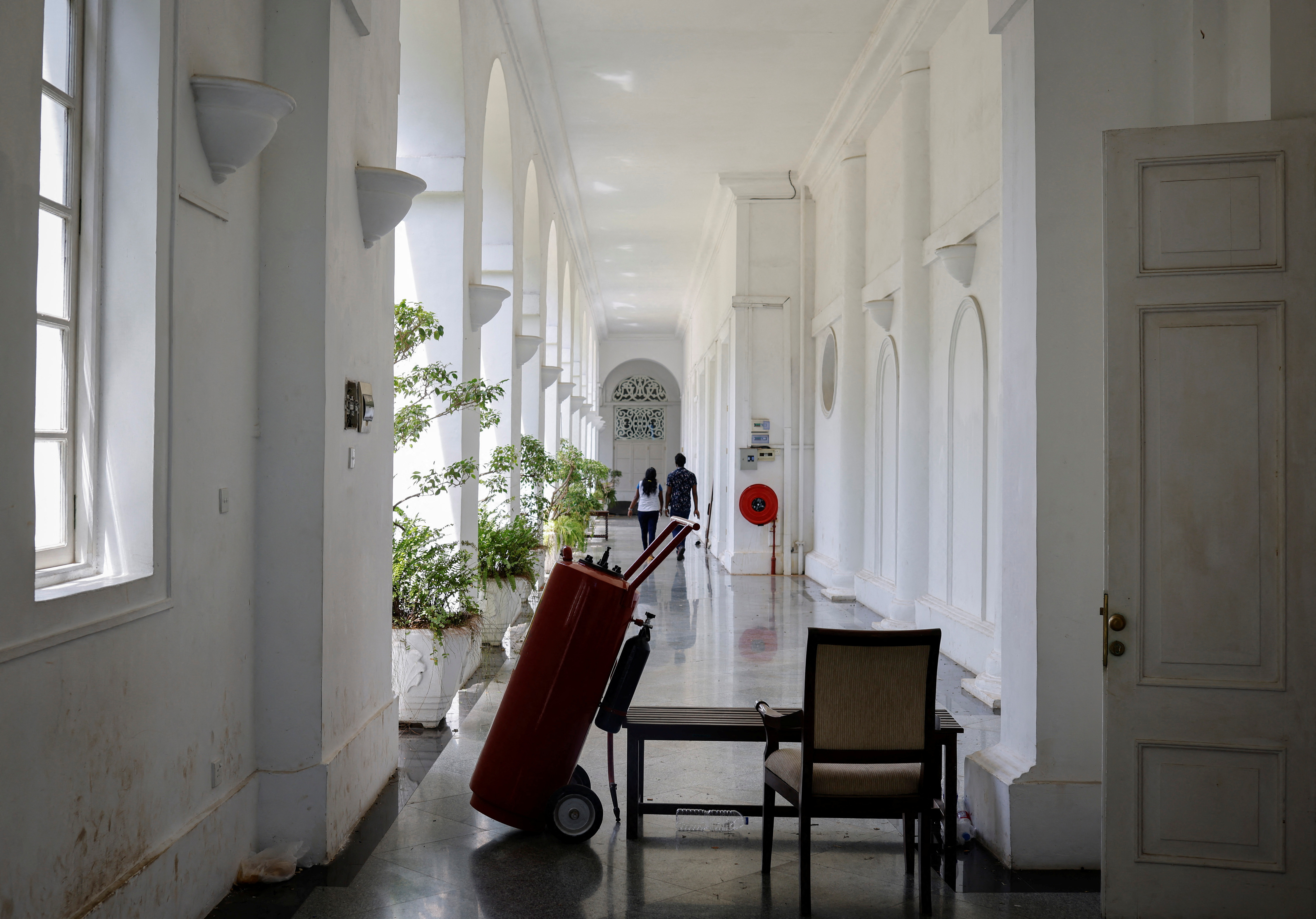 People walk as a fire extinguisher blocks a way inside the President Rajapaksa's house in Colombo