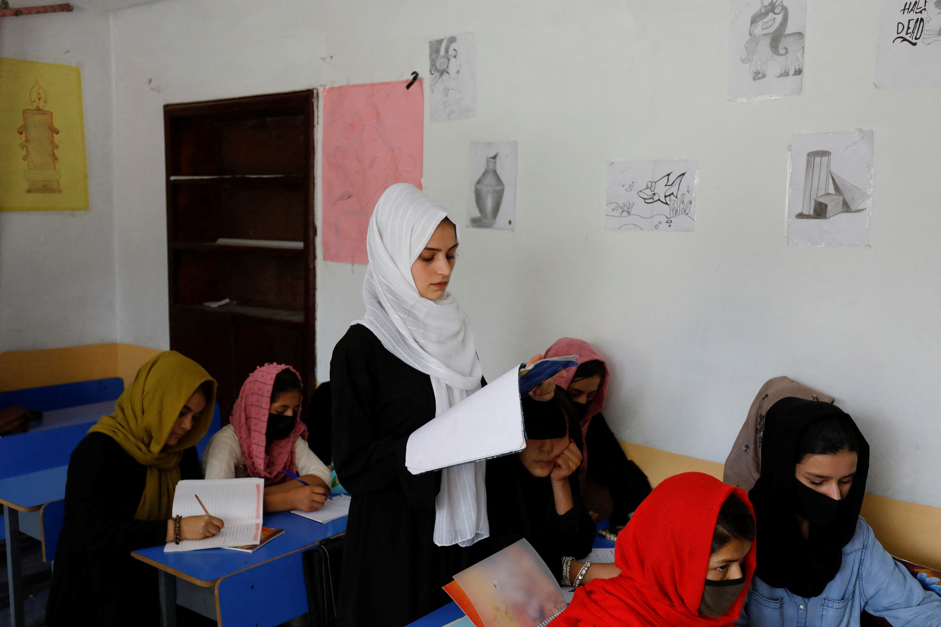 Kerishma Rasheedi, 16, reads during a class at a private school class in Kabul
