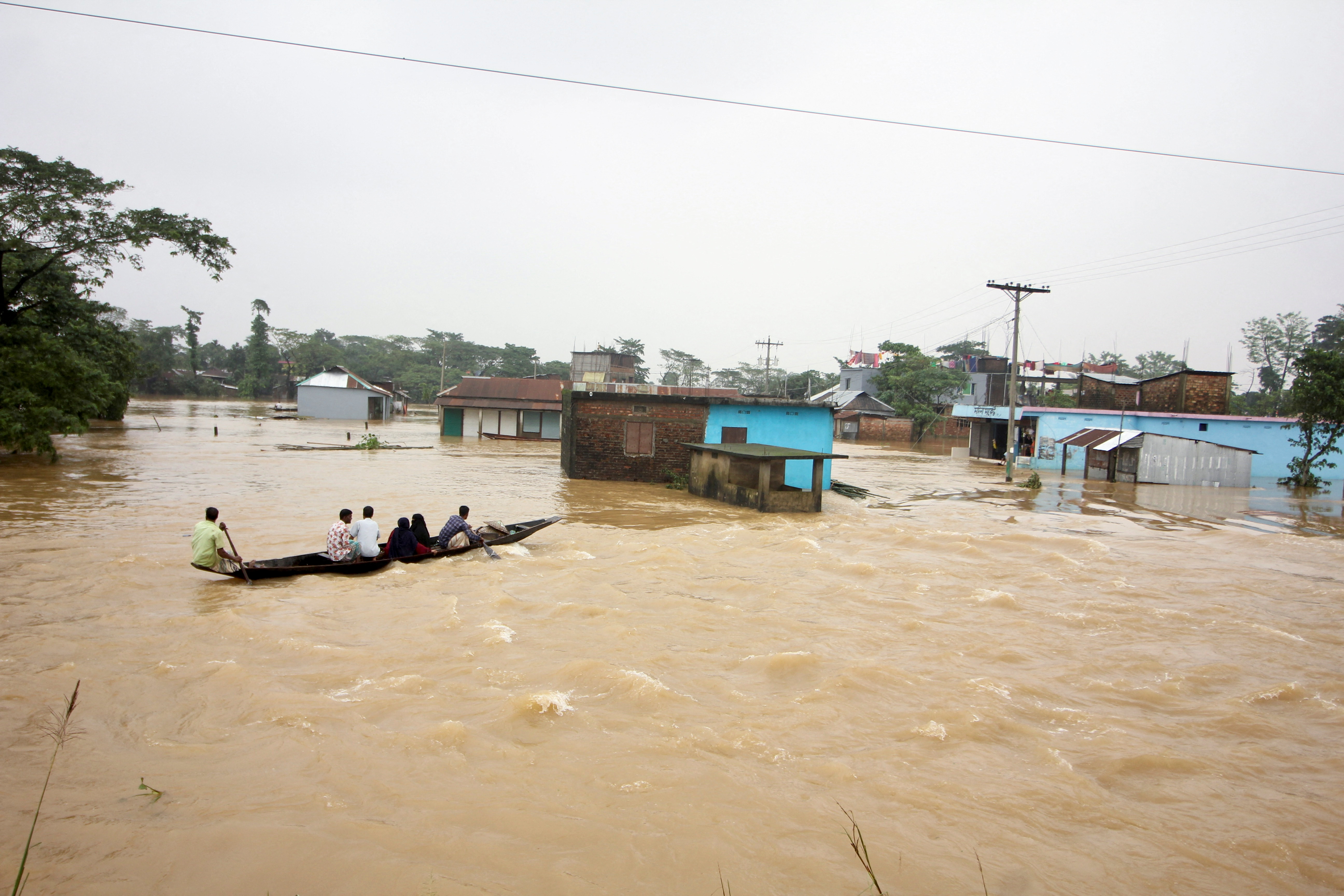People move a boat in a flooded area during a widespread flood in Sylhet