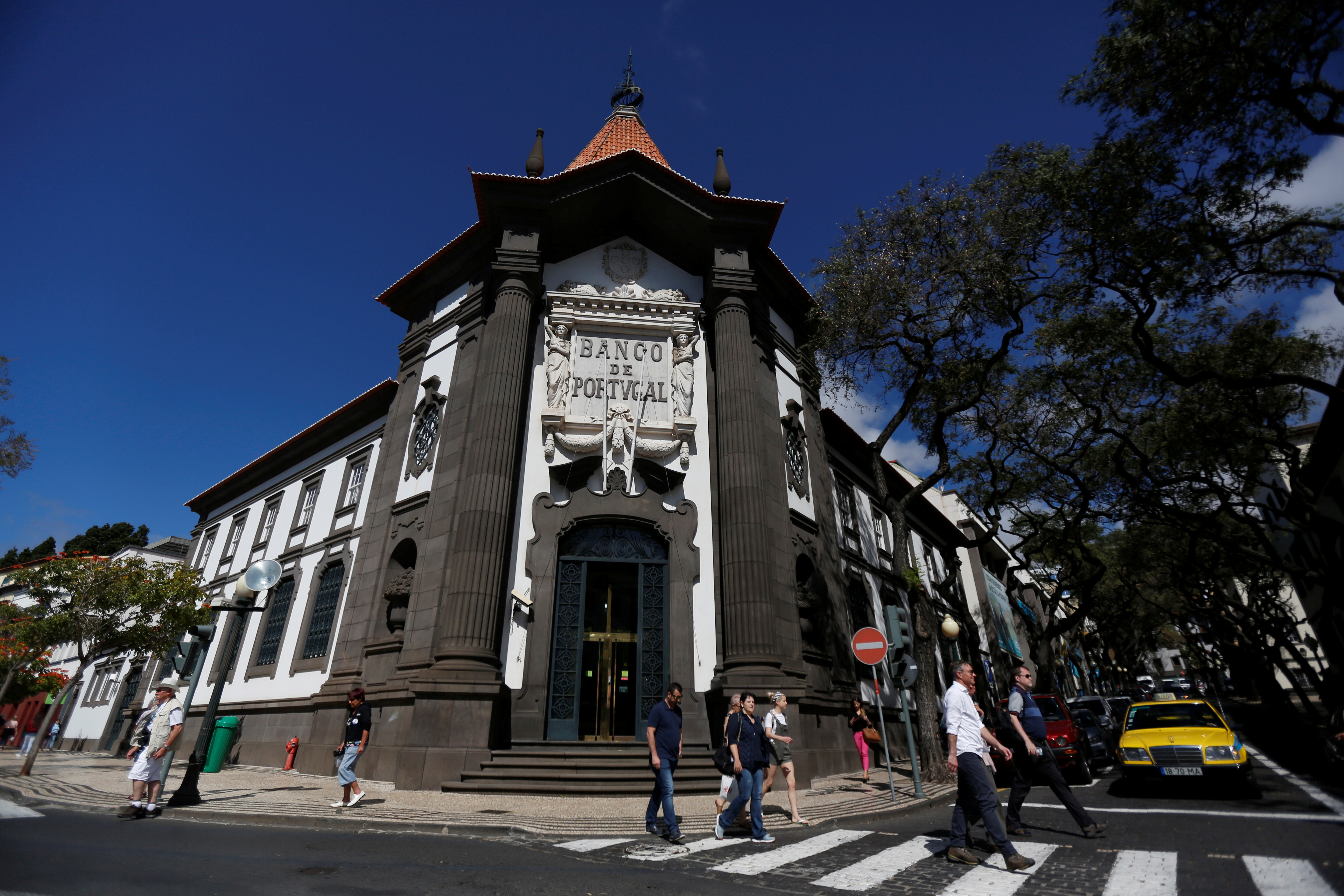 Pessoas caminham perto do Banco de Portugal, no centro do Funchal