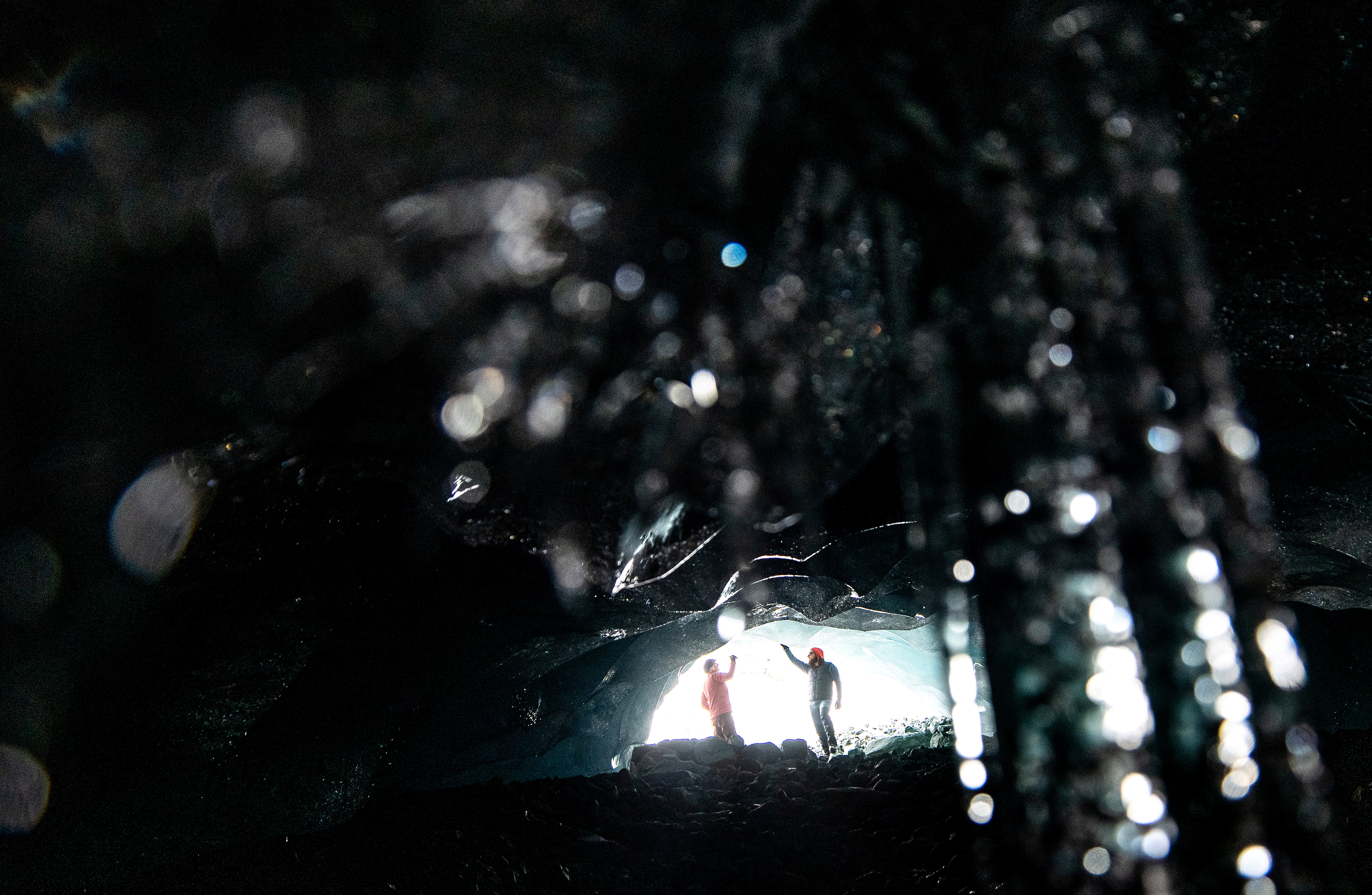 Glaciologists Andrea Fischer and Martin Stocker-Waldhuber, from the Austrian Academy of Sciences, inspect the entrance of a natural glacier cavity of the Jamtalferner glacier near Galtuer, Austria, October 15, 2021. Giant ice caves have appeared in glaciers accelerating the melting process faster than expected as warmer air rushes through the ice mass until it collapses. Picture taken October 15, 2021. REUTERS/Lisi Niesner