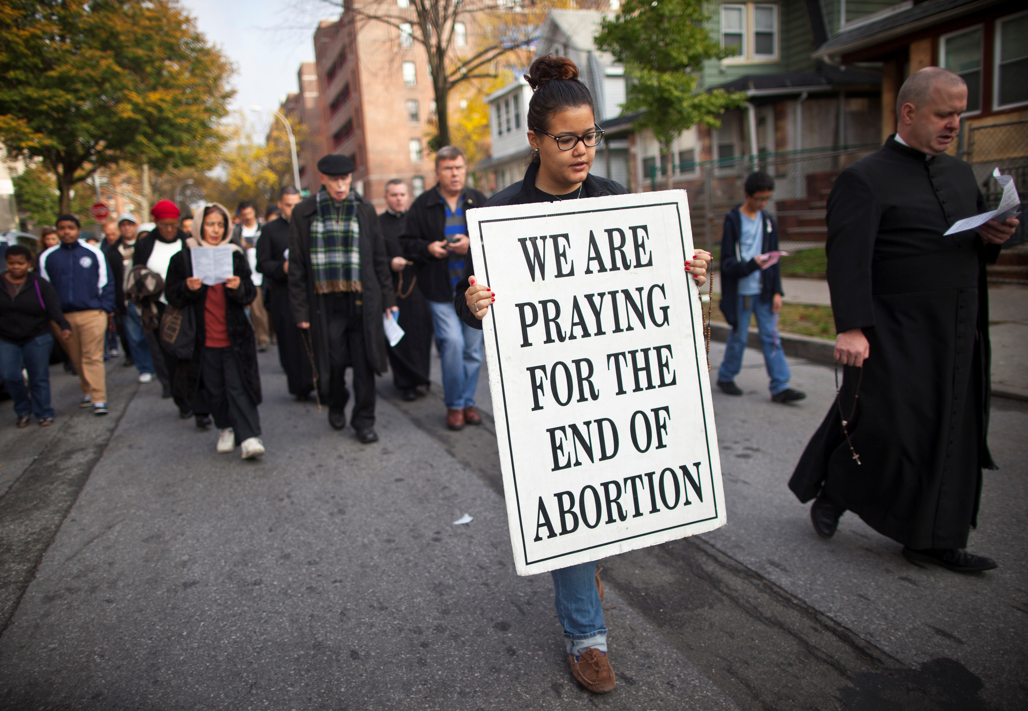 A woman holds a sign during an anti-abortion protest march to the Choices Women's Medical Center in Queens