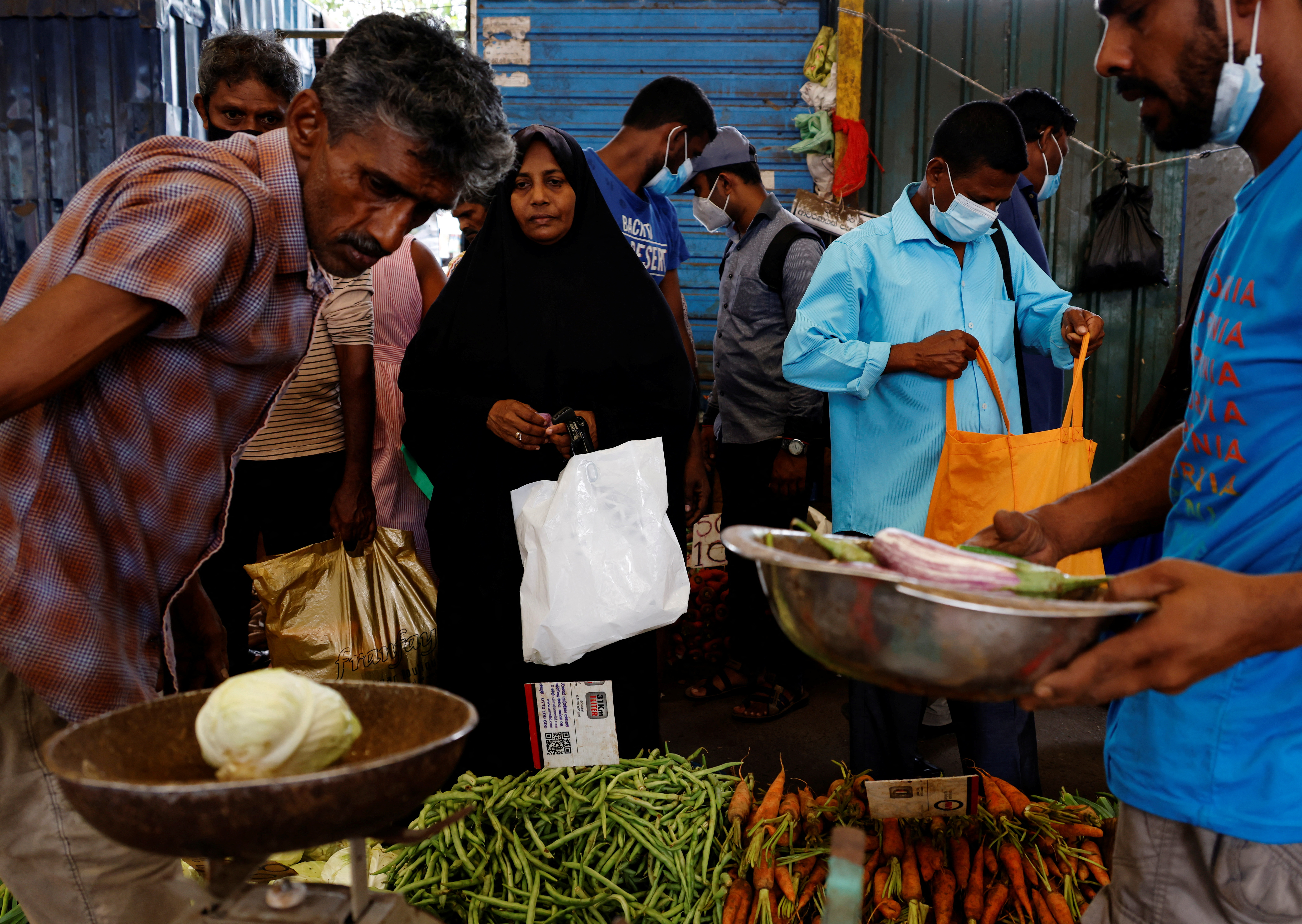 EA woman buys vegetables from a vendor at a market in the rampant food inflation, amid Sri Lanka's economic crisis, in Colombo