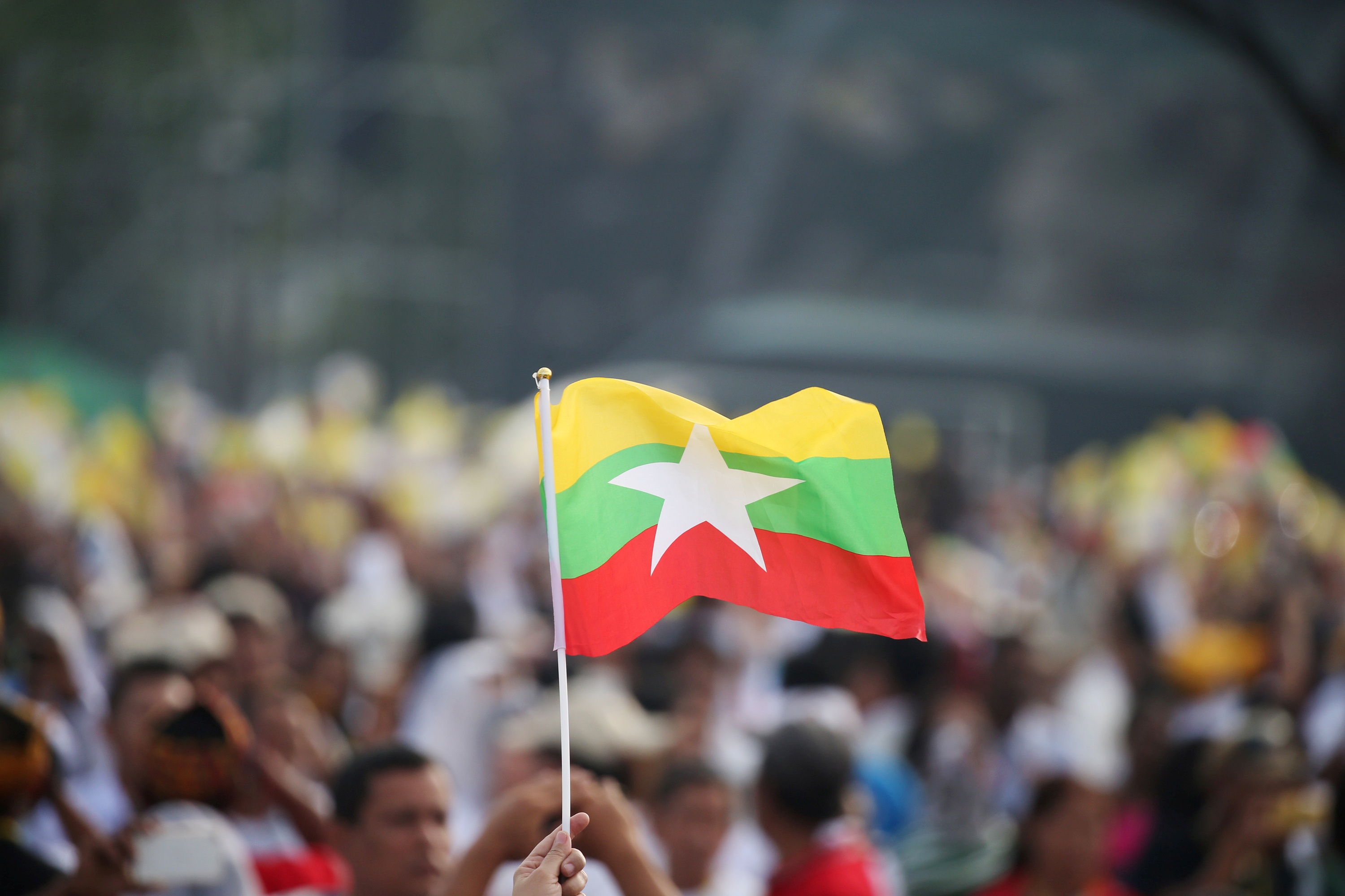 A Catholic faithful waves a Myanmar flag as Pope Francis arrives to lead a mass at Kyite Ka San Football Stadium in Yangon, Myanmar