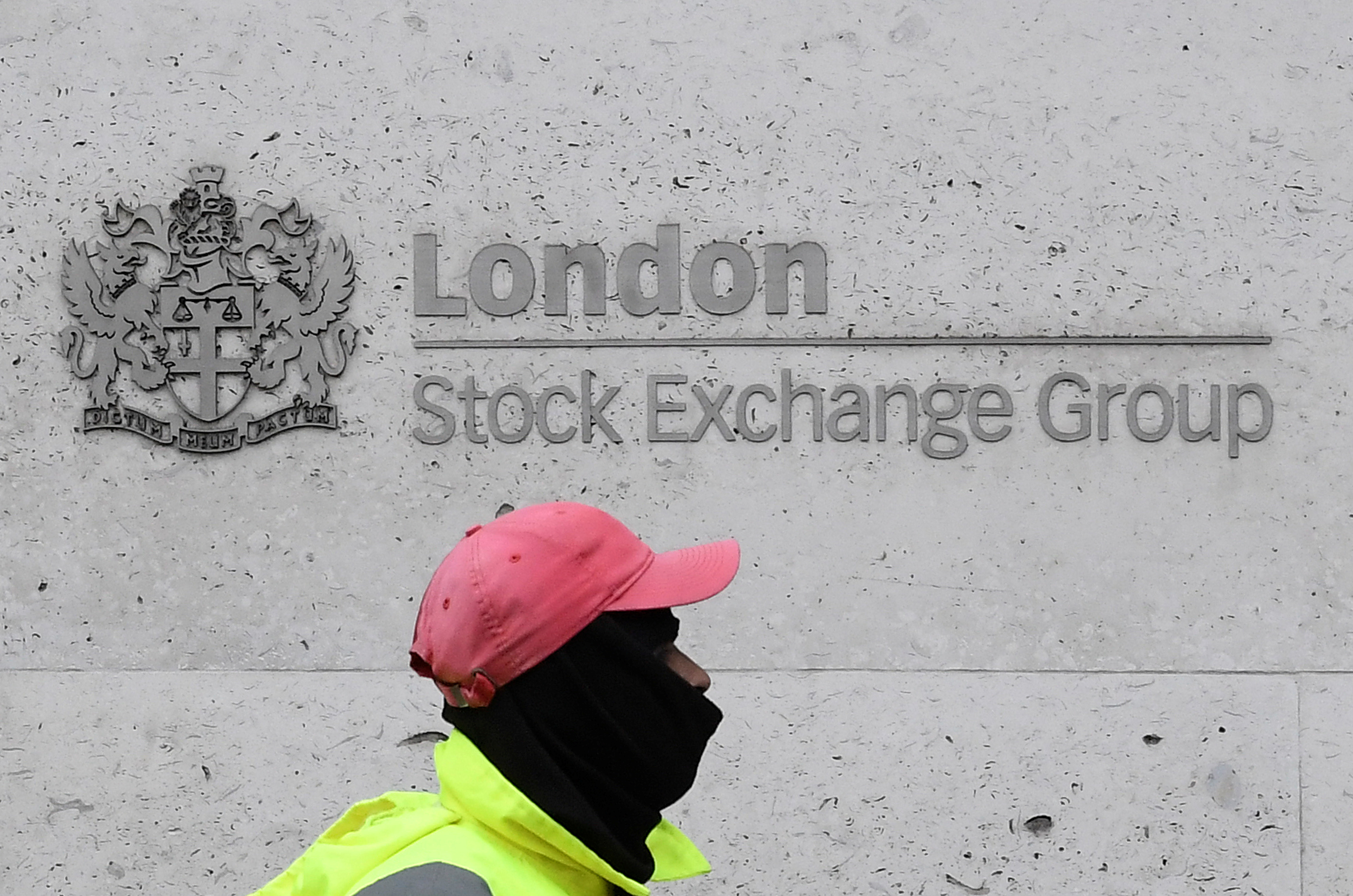 A street cleaning operative walks past the London Stock Exchange Group building in the City of London financial district, whilst British stocks tumble as investors fear that the coronavirus outbreak could stall the global economy, in London