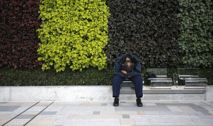 A man takes a nap at a bench at a street in Tokyo