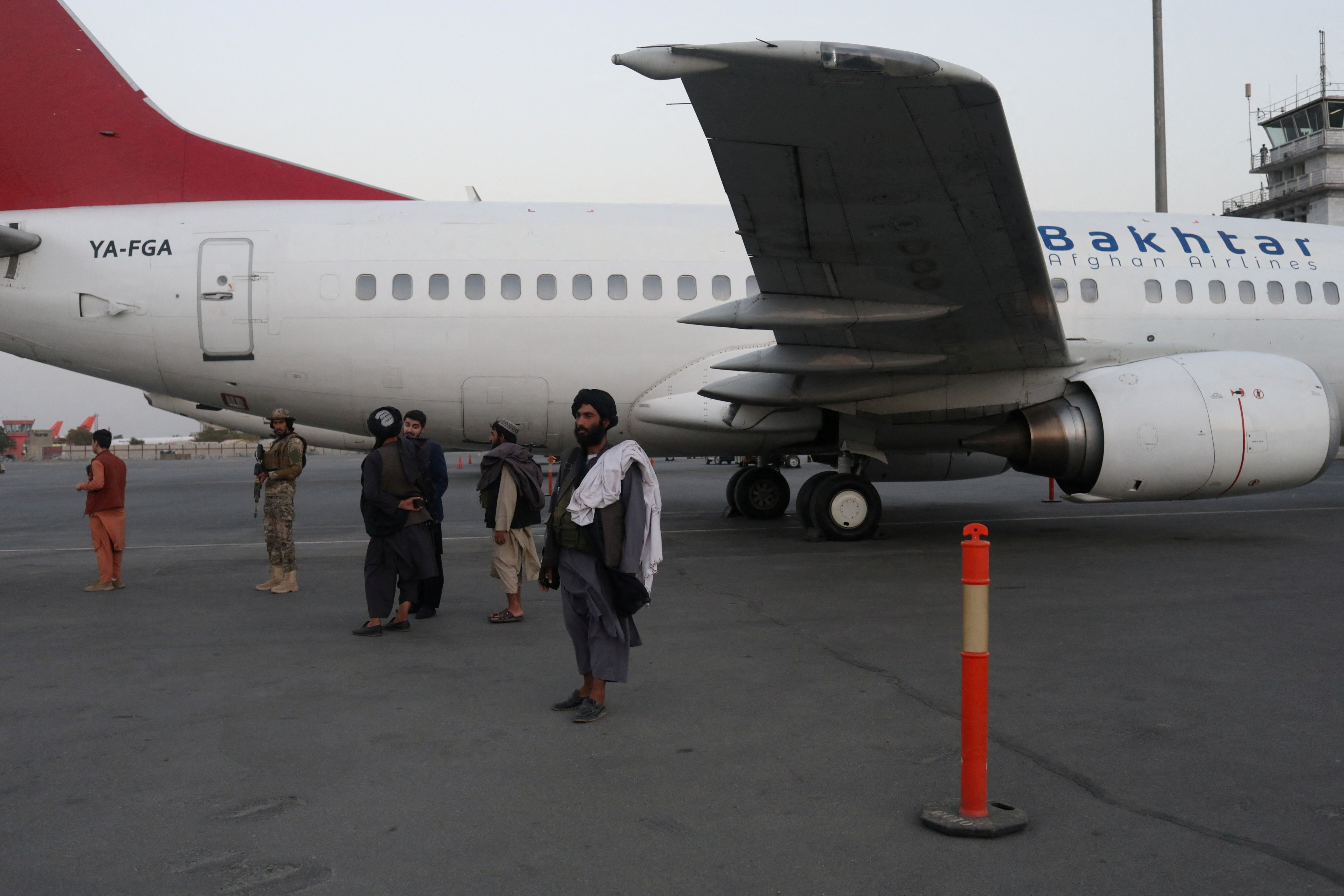 Taliban members stand on airport runway in Kabul