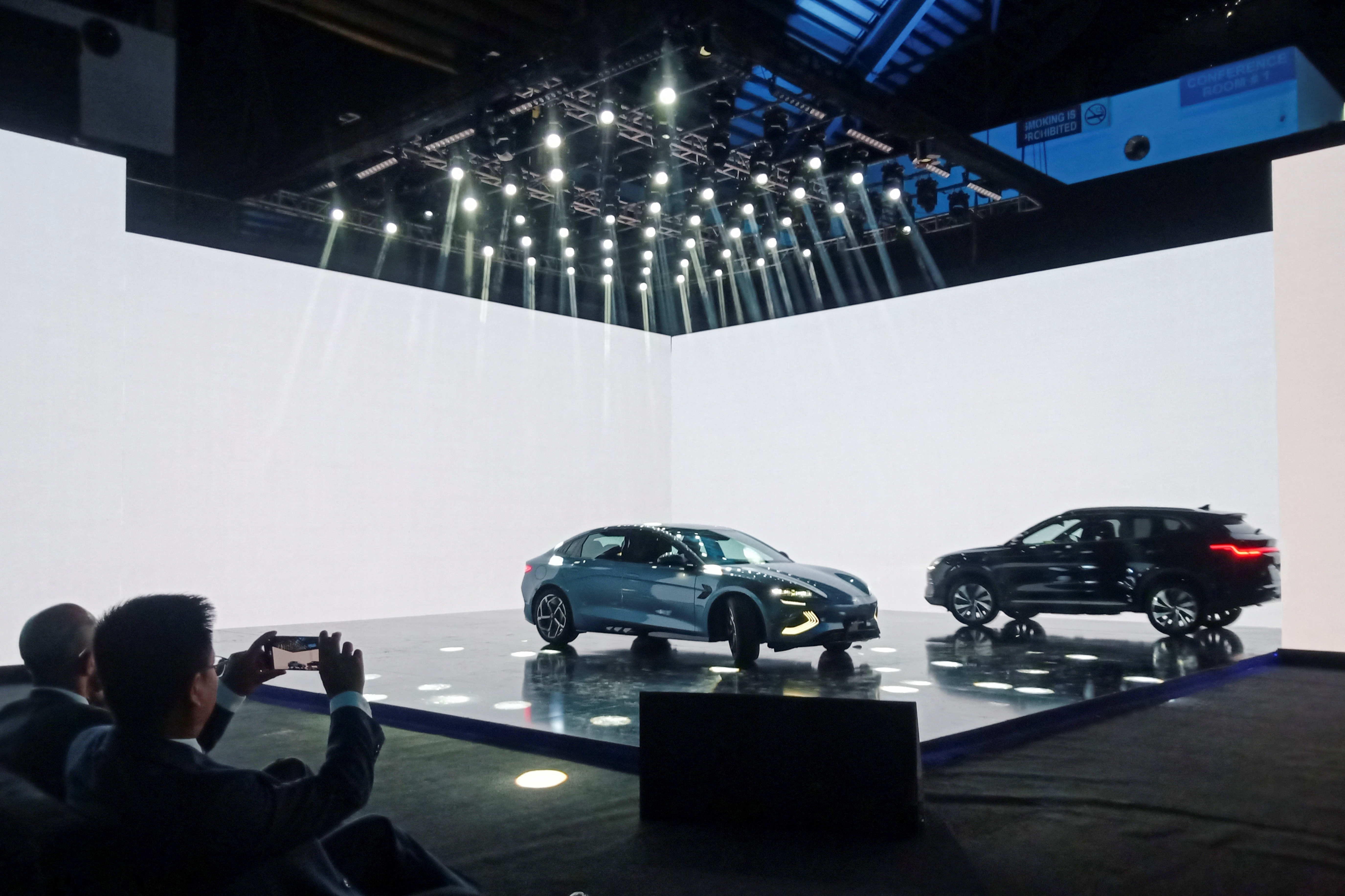 An attendee takes photos of the Chinese electric vehicle BYD models on display, during an event to announce the plans to open a car production plant in Pakistan, in Lahore