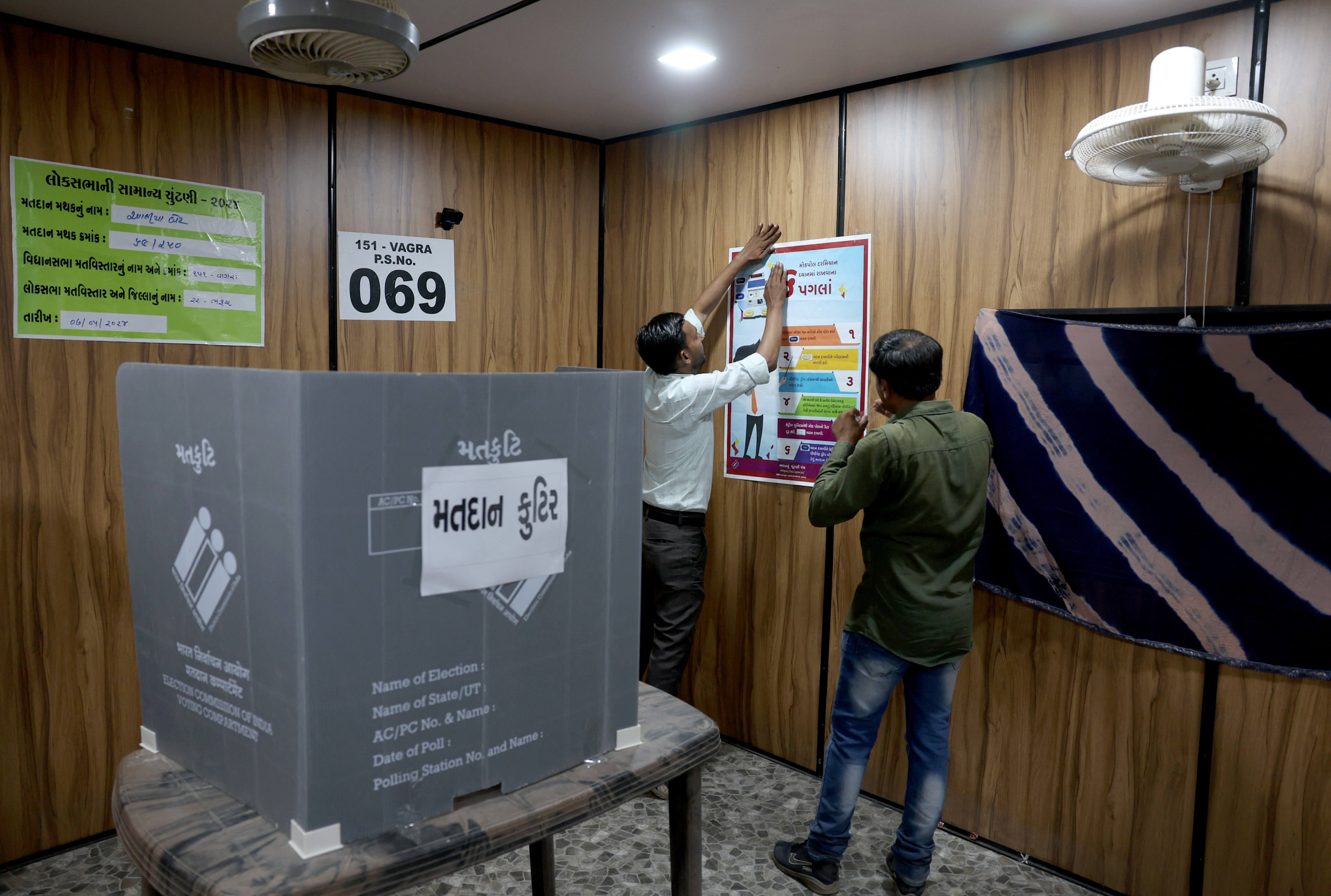 Polling officials set up a polling booth inside a shipping container, ahead of the third phase of India's general election, at Aaliya Bet Island