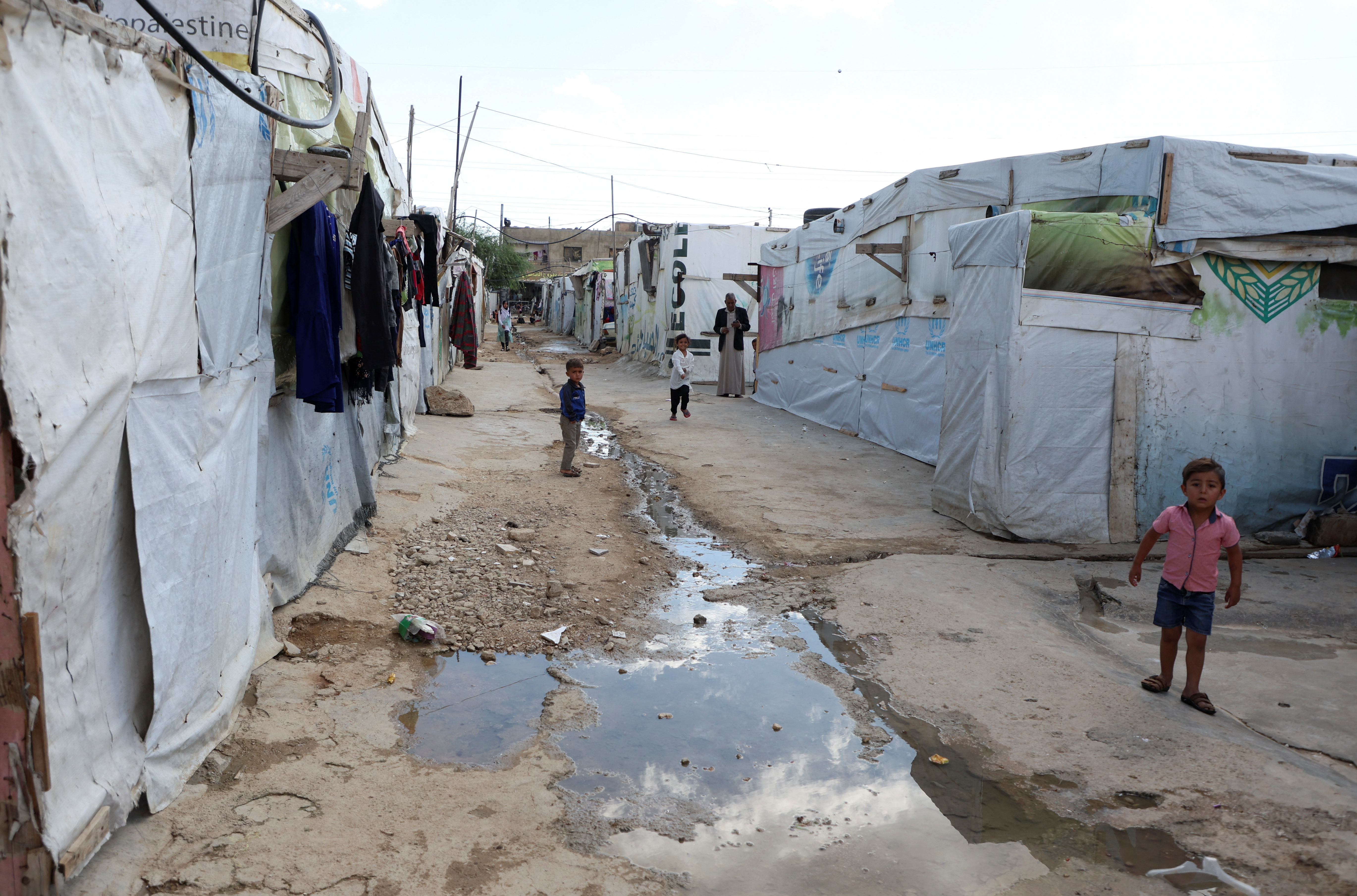 Syrian refugee children stand near water way at an informal camp in Qab Elias