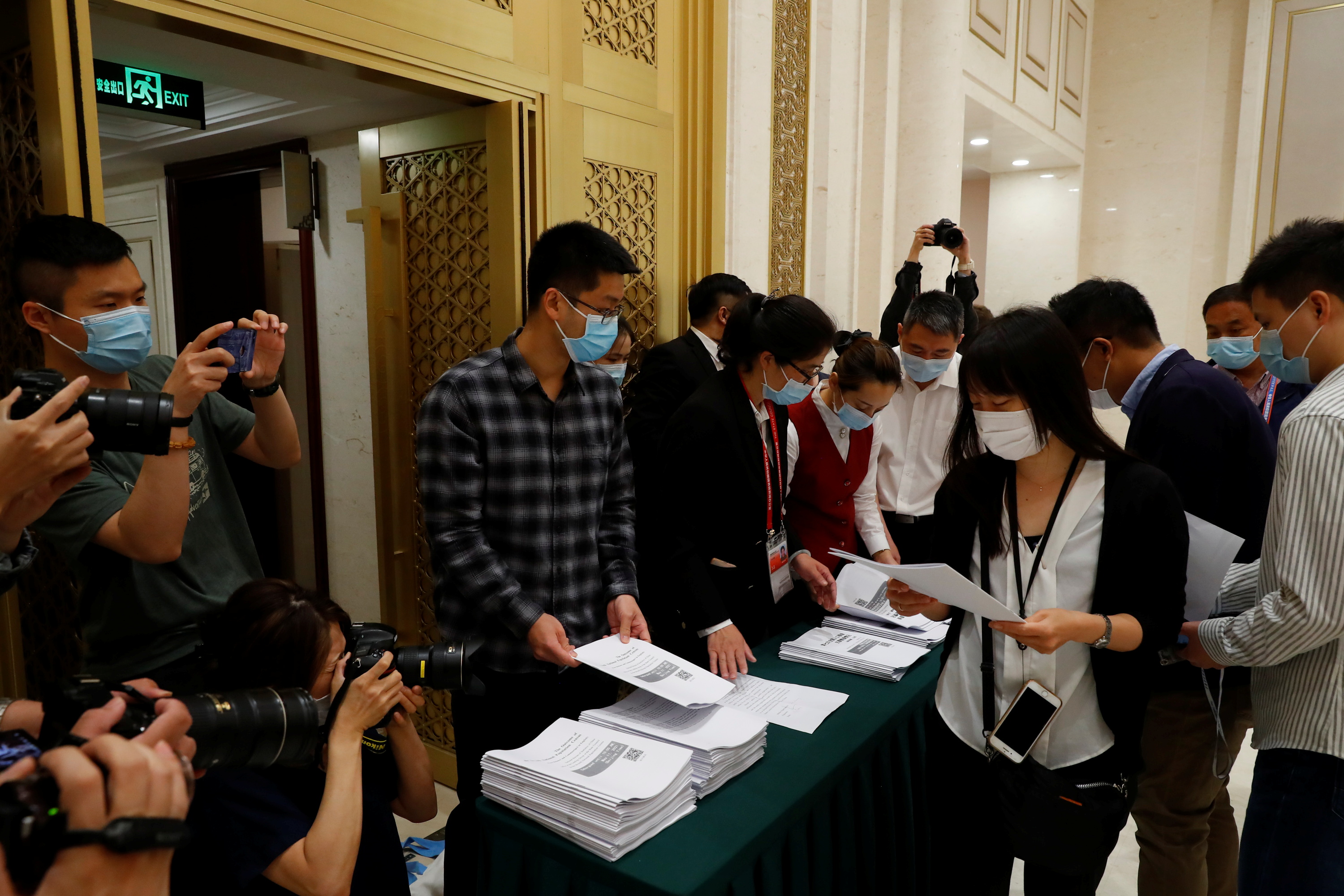 Journalists pick up a copy of China's National Bureau of Statistics population census report before a news conference in Beijing