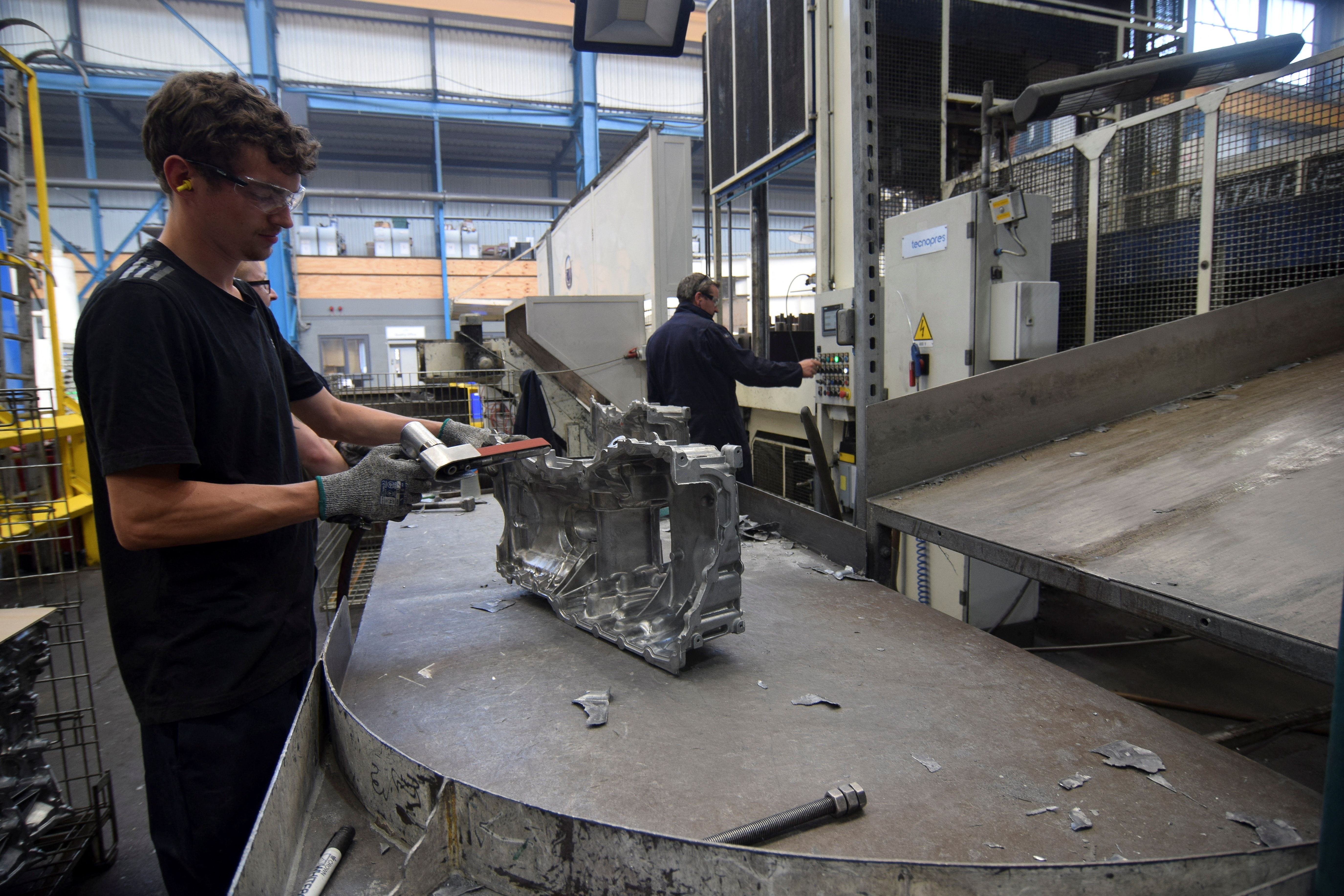 A worker at Evtec Aluminium Ltd sands excess metal off a freshly made aluminium part at the company's foundry, in Kidderminste