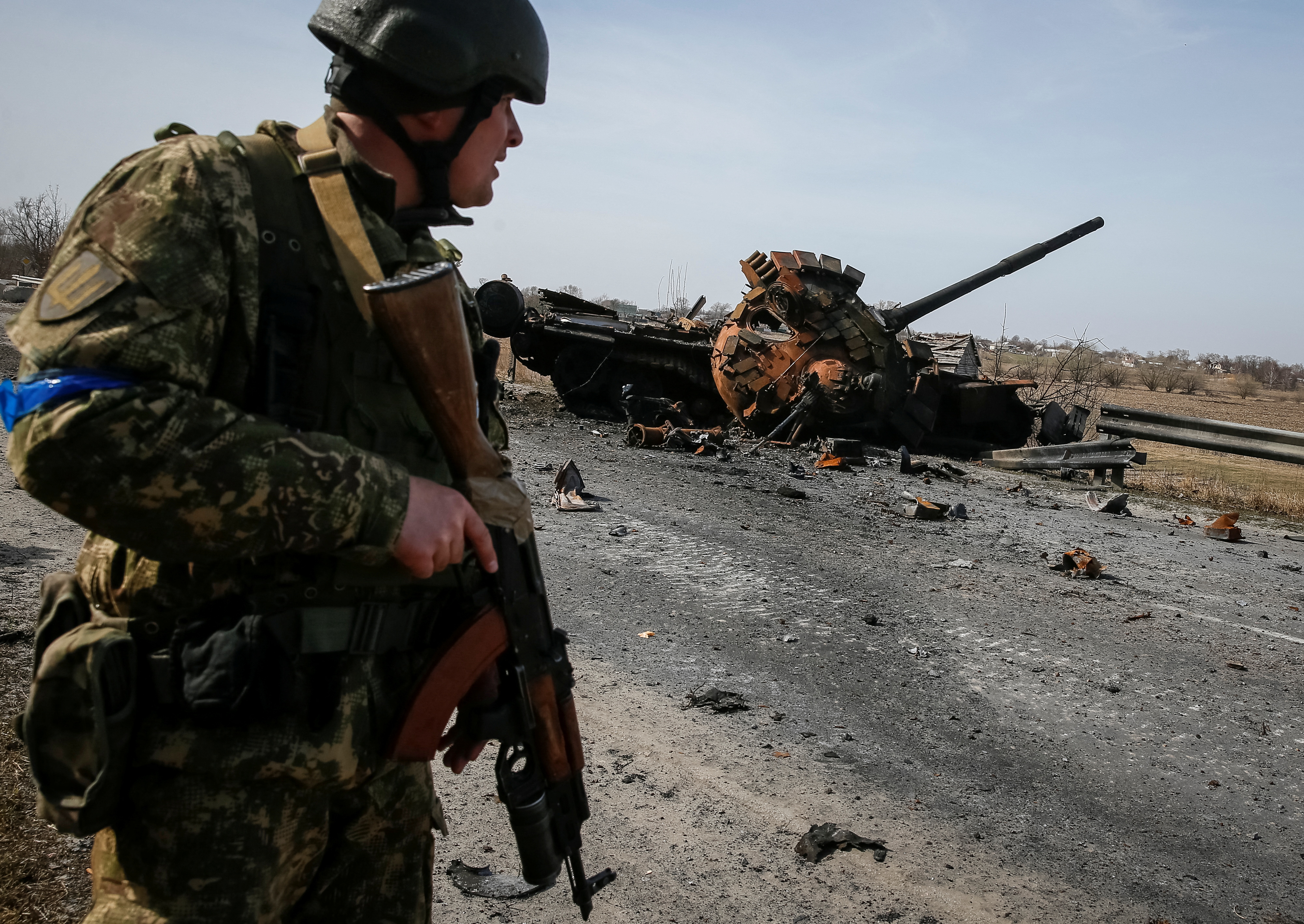 A Ukrainian serviceman stands near the wreck of a Russian tank on the front line in the Kyiv region