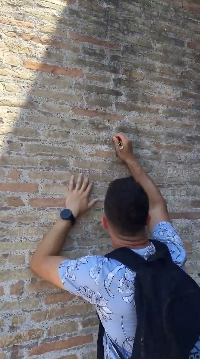 Tourist carves on the wall of the Colosseum in Rome