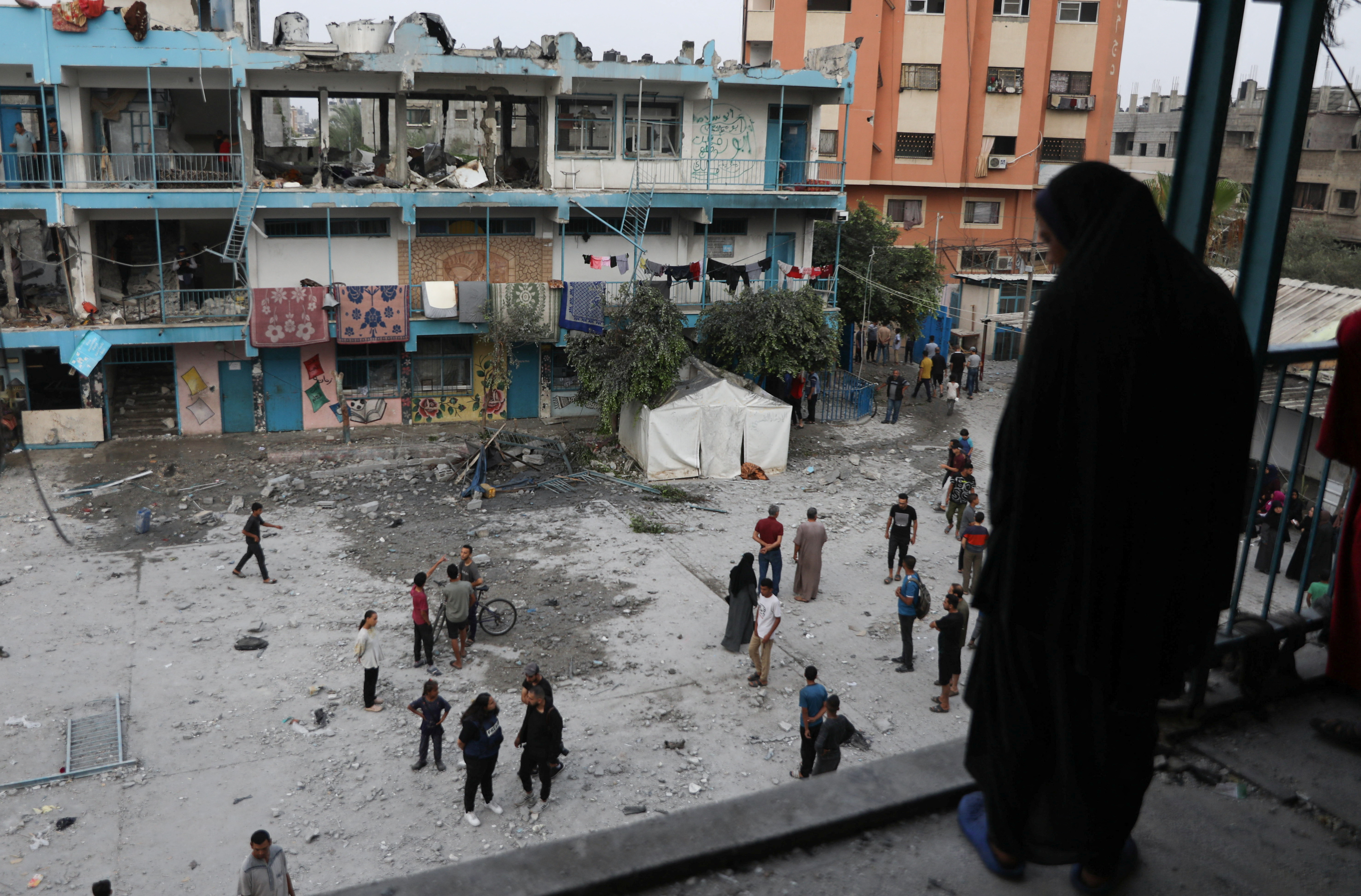 Palestinians inspect the site of an Israeli strike on a UNRWA school sheltering displaced people, in Nuseirat refugee camp