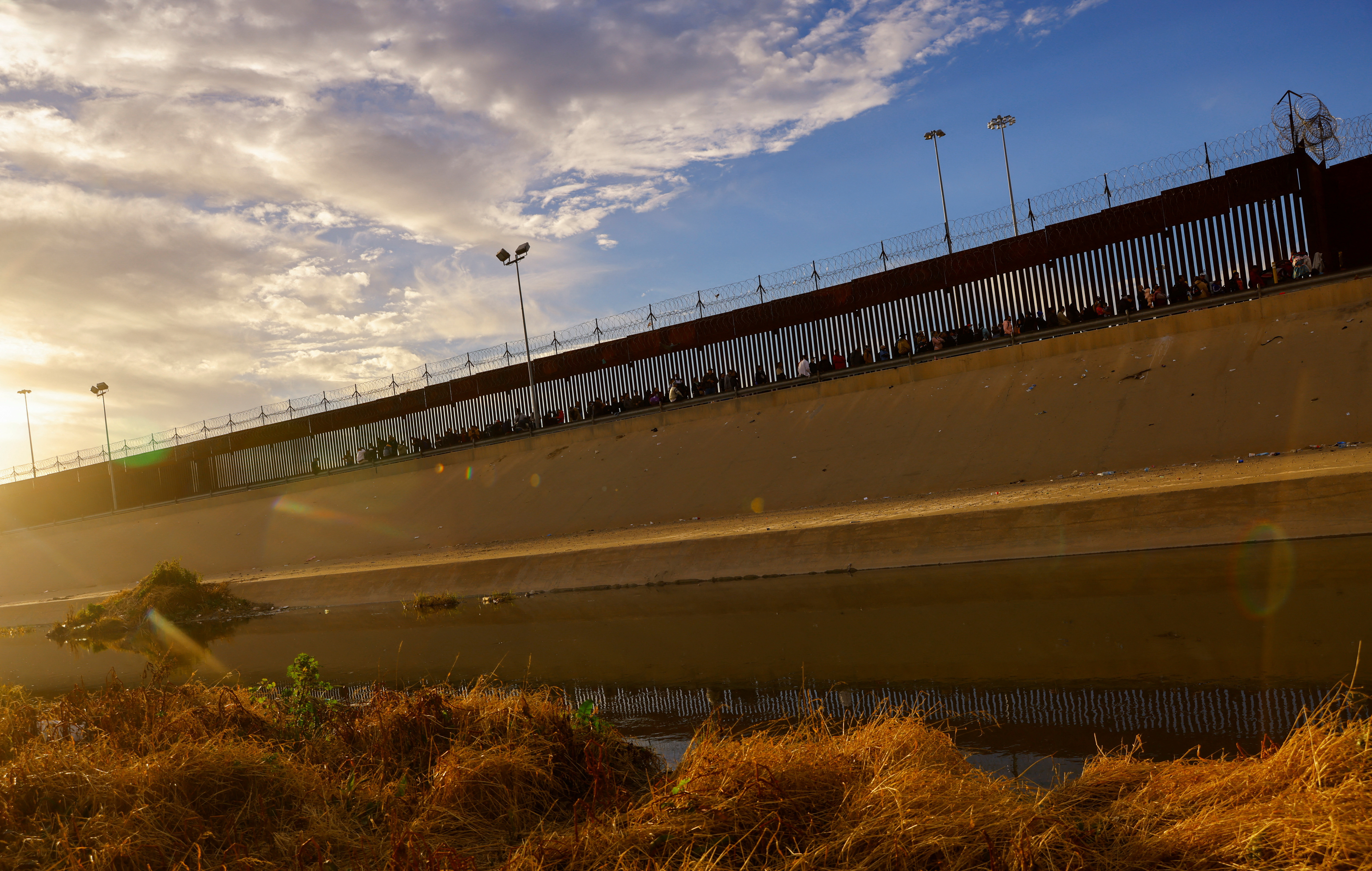 Migrants queue near the border fence, after crossing the Rio Bravo river, in Ciudad Juarez