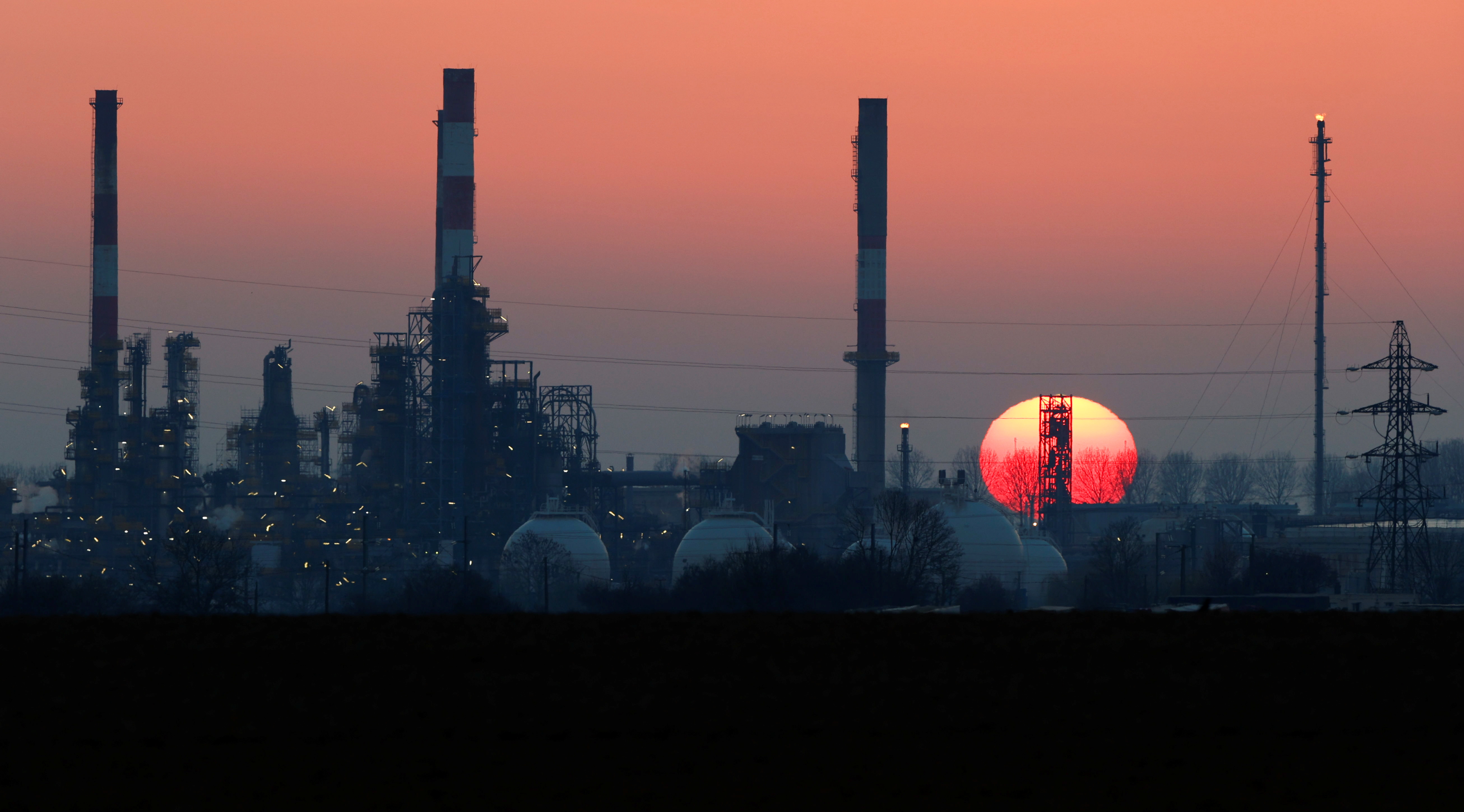 The sun sets behind the chimneys of the Total Grandpuits oil refinery, southeast of Paris, France, March 1, 2021.  REUTERS/Christian Hartmann