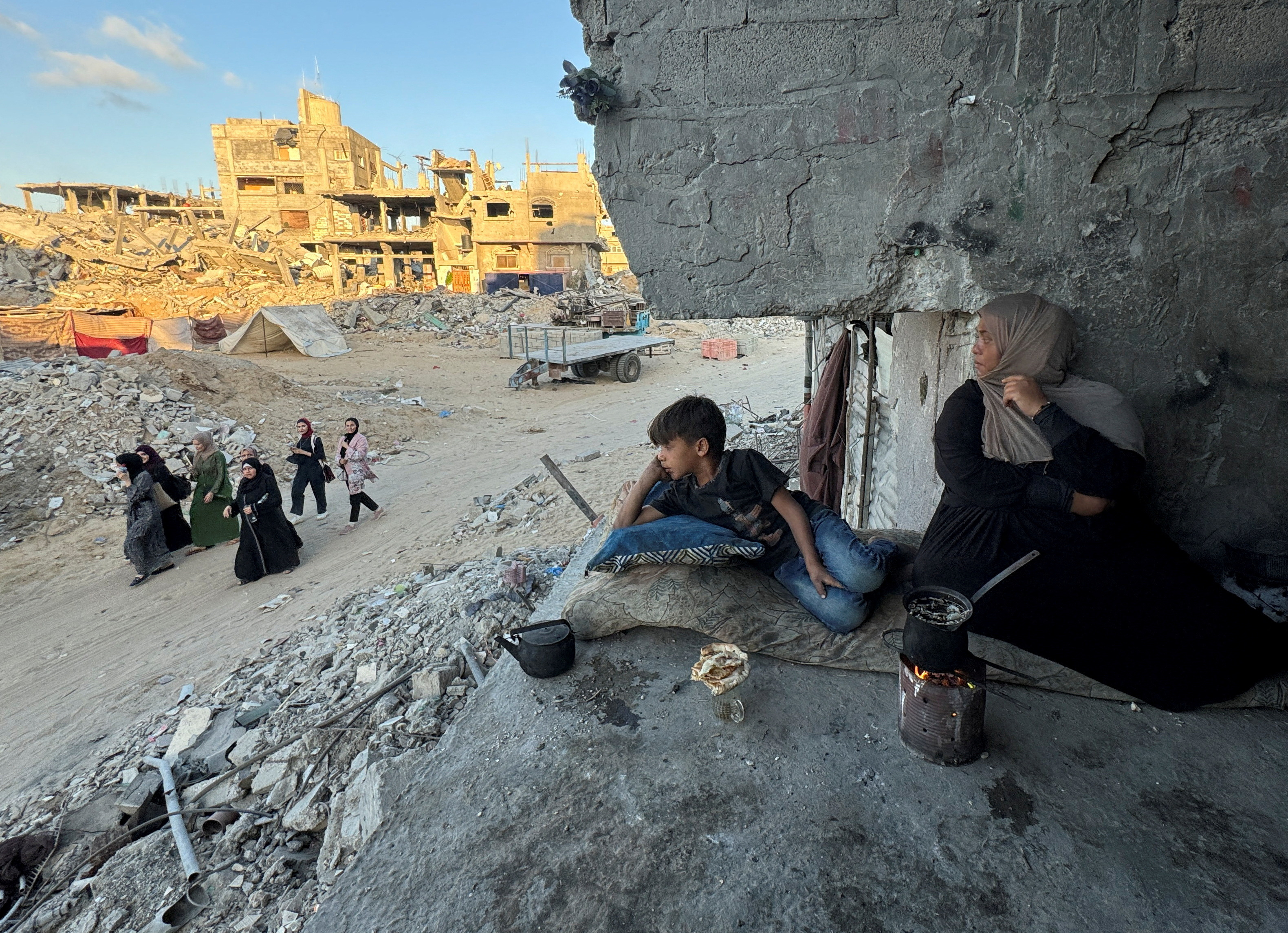 Palestinians sit at their houses, destroyed in Israeli strikes, in Khan Younis