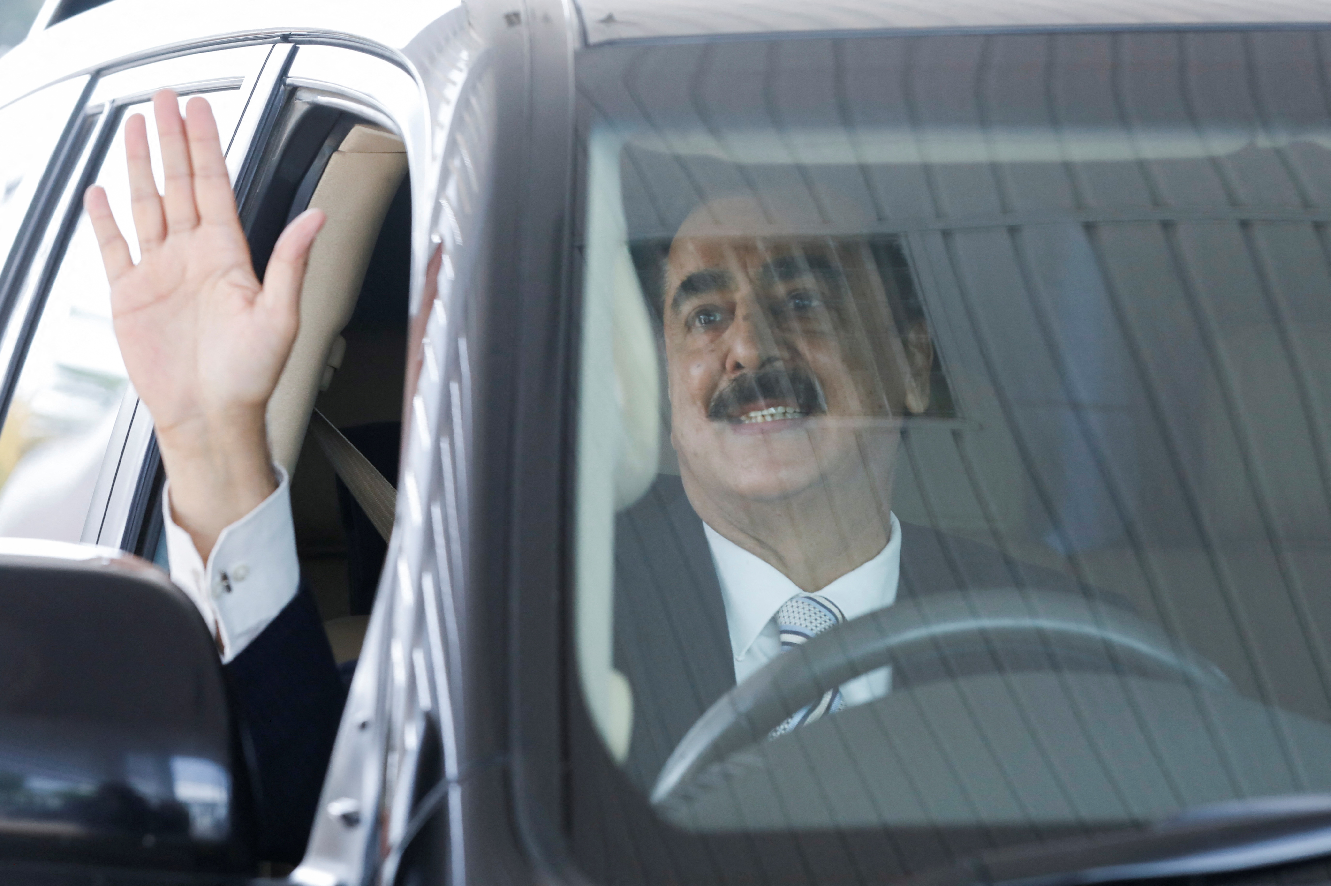 Pakistan's former Prime Minister Yousaf Raza Gilani and leader of the Pakistan People's Party (PPP) waves to the cameras as he arrives at the Parliament House building in Islamabad,