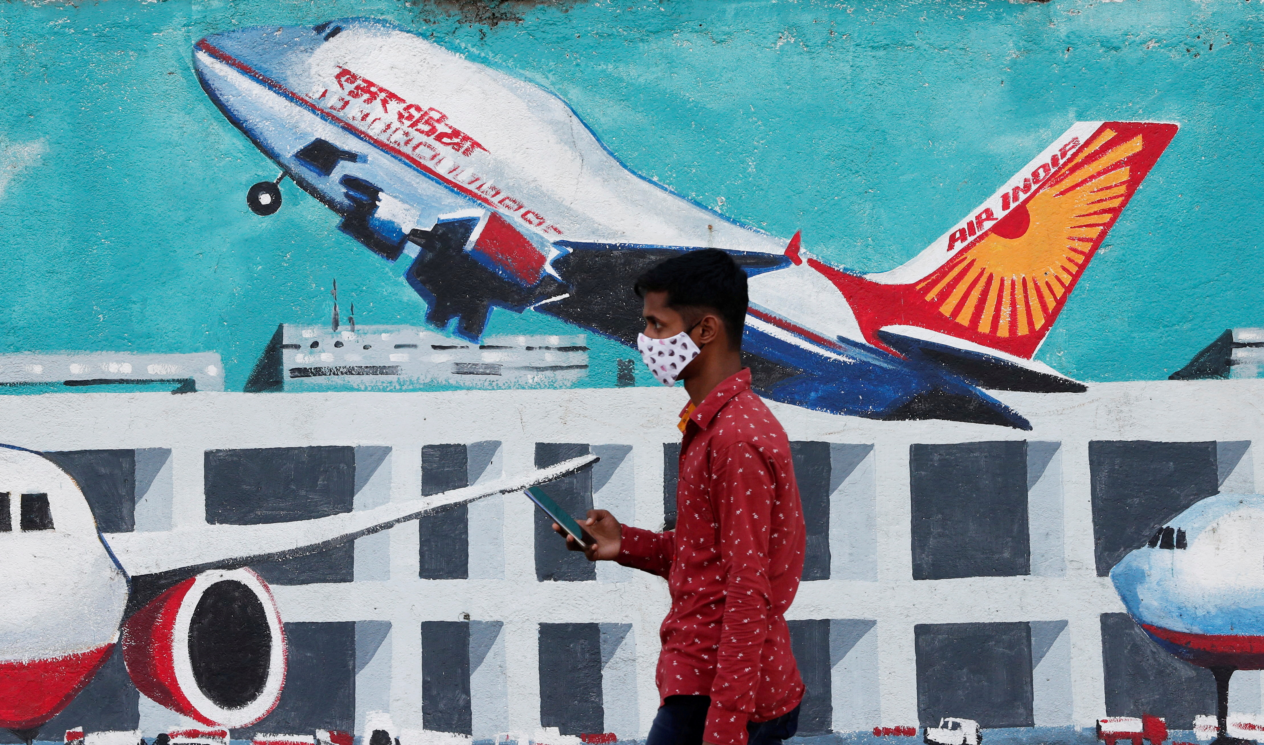 A man walks past a mural of Air India airlines on a street in Mumbai