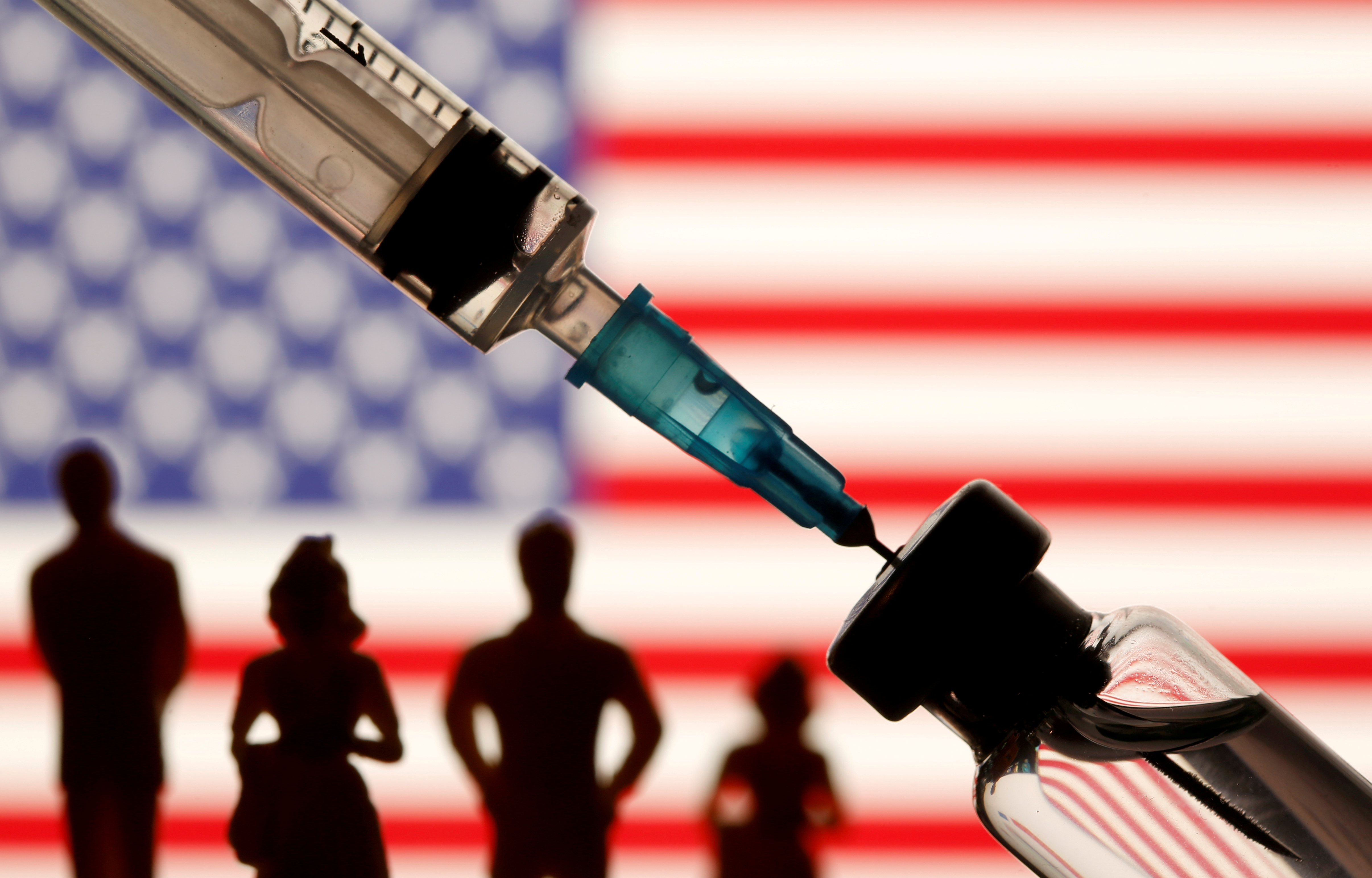 A vial, syringe and small toy figures are seen in front of a displayed U.S. flag in this illustration taken January 11, 2021. REUTERS/Dado Ruvic/Illustration/File Photo