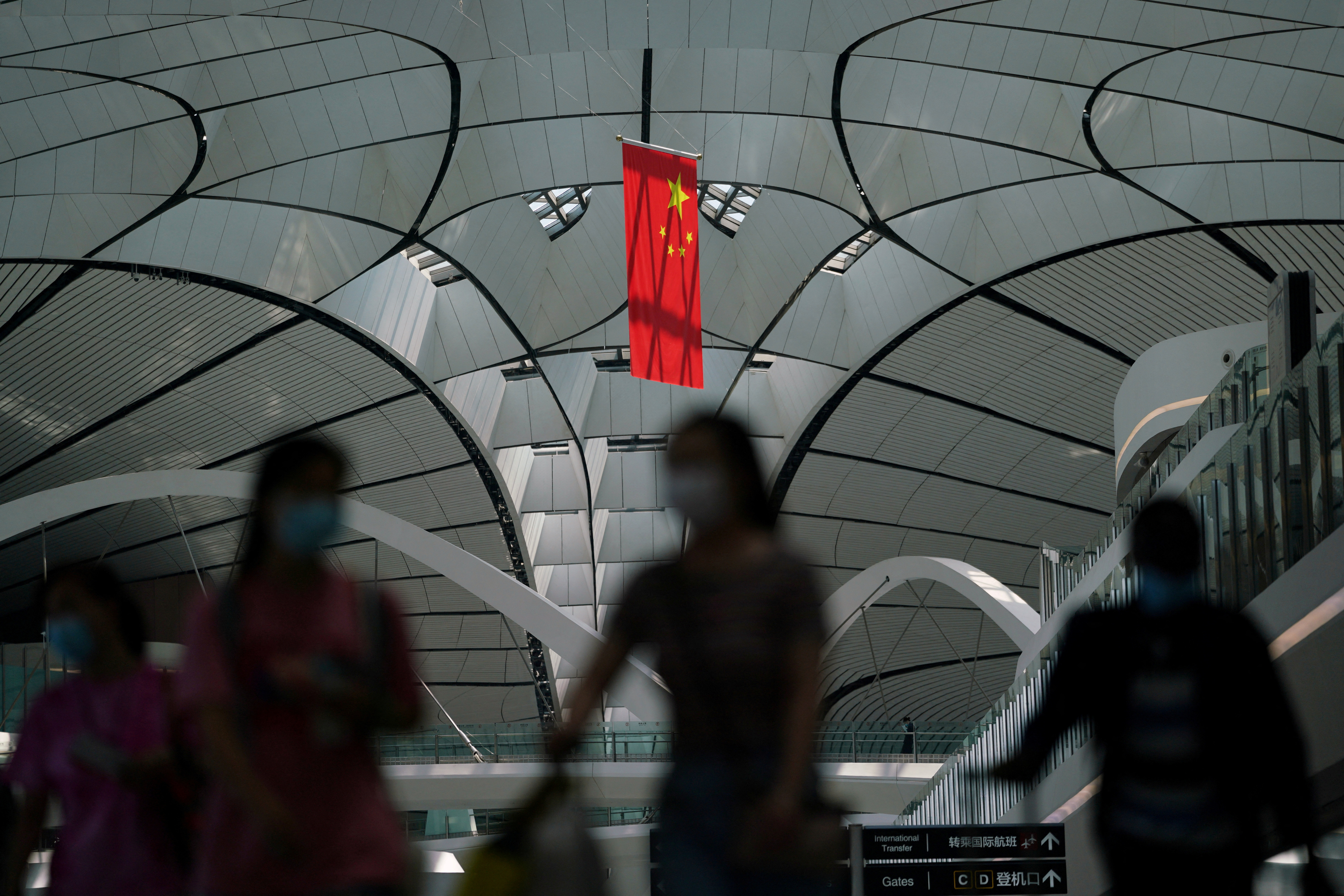 People wearing face masks walk under a Chinese flag at Beijing 