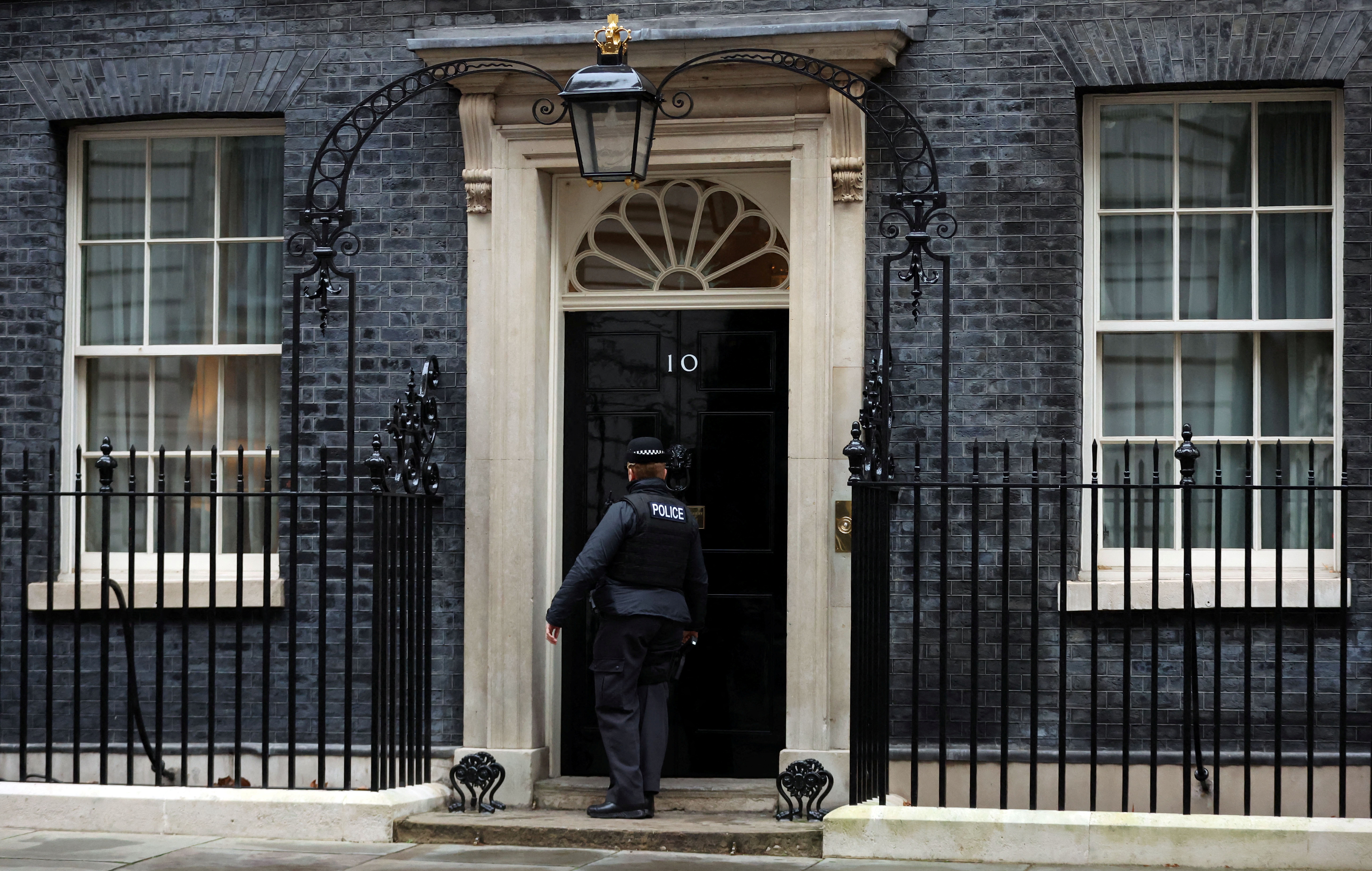 A police officer knocks on the door of Downing Street in London, Britain, January 11, 2022. REUTERS/Hannah McKay