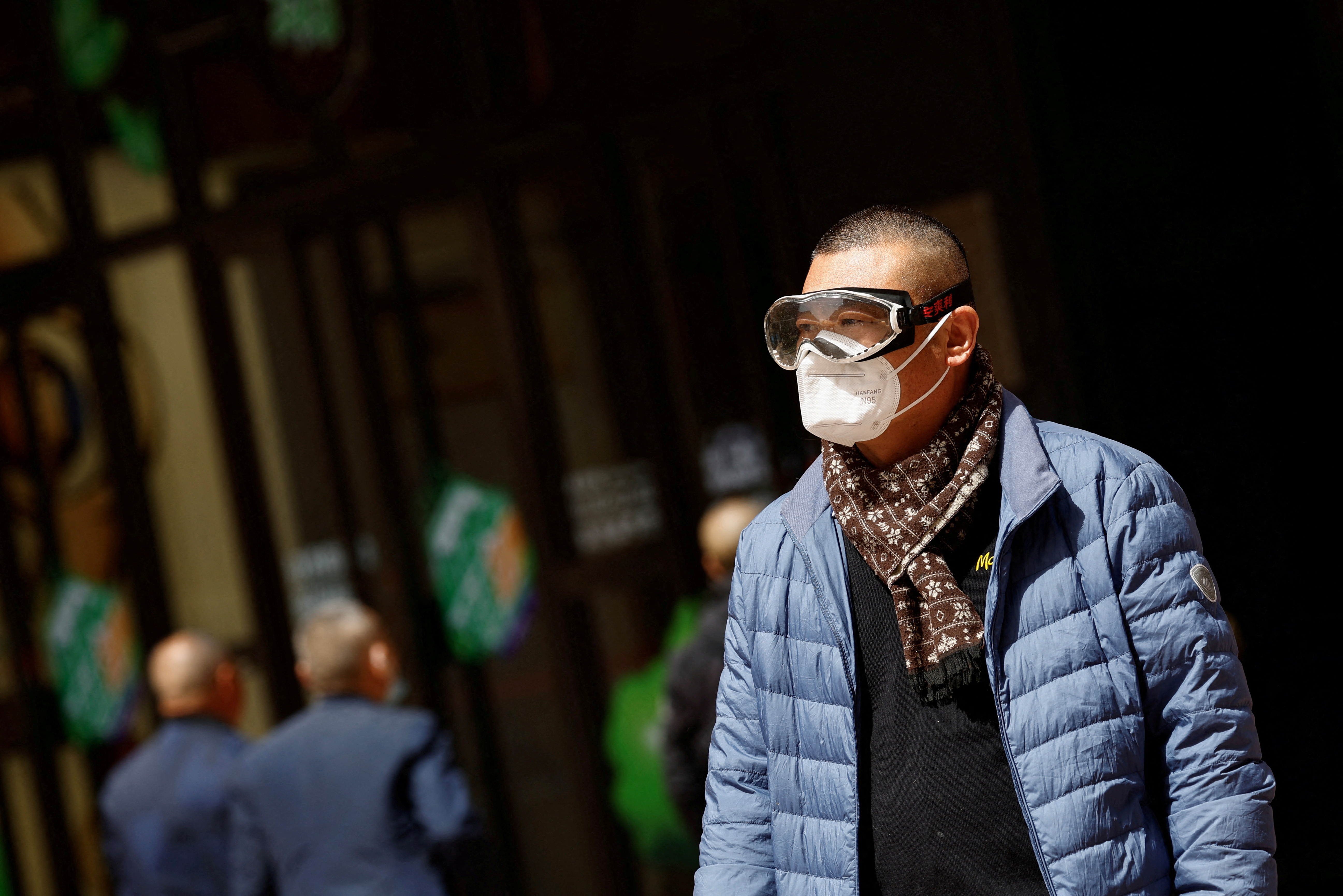 Man wearing a pair of protective goggles walking amid a sandstorm in Beijing