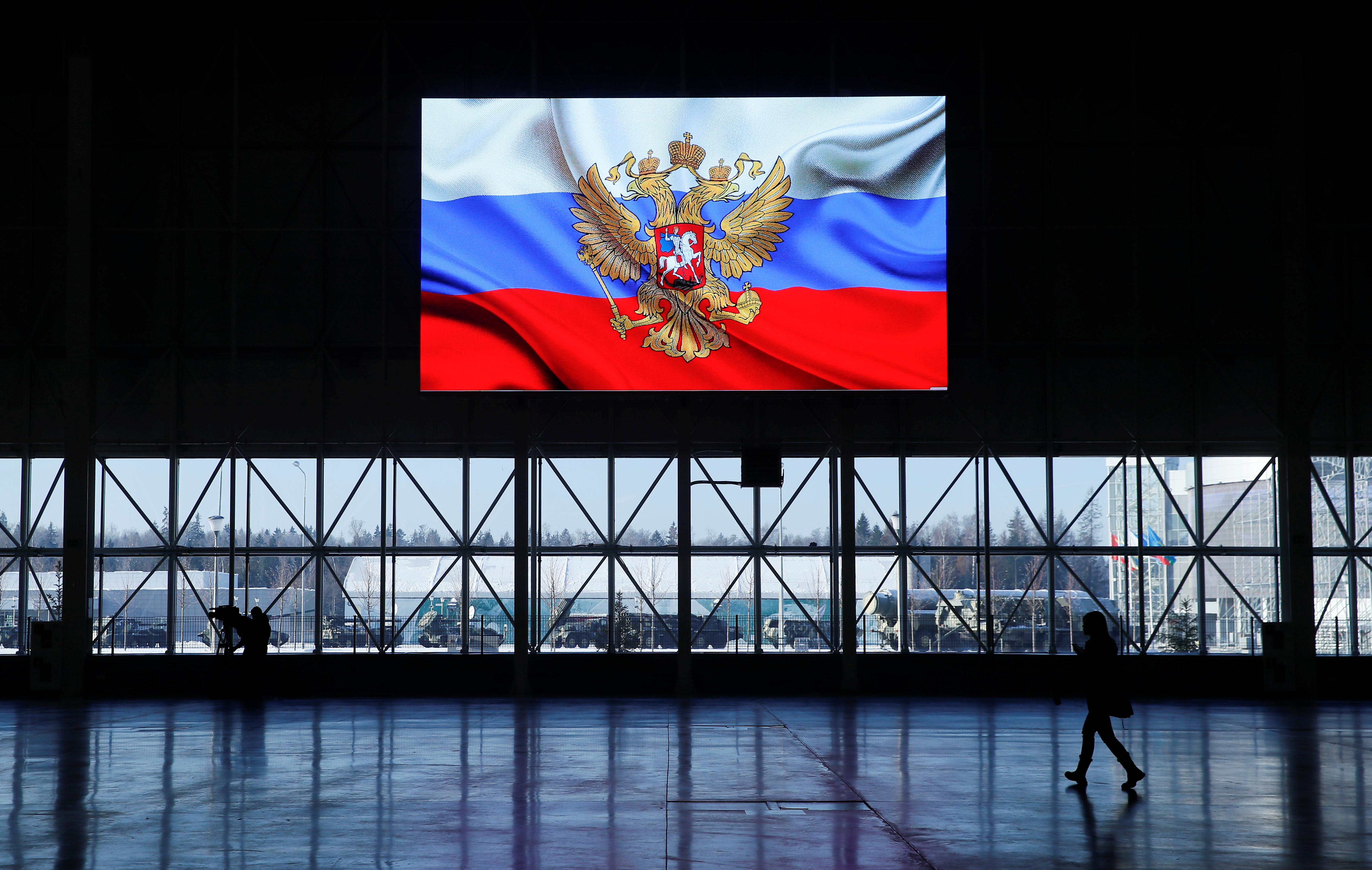 A view shows a screen displaying a flag with the Russian coat of arms during a news briefing near Moscow