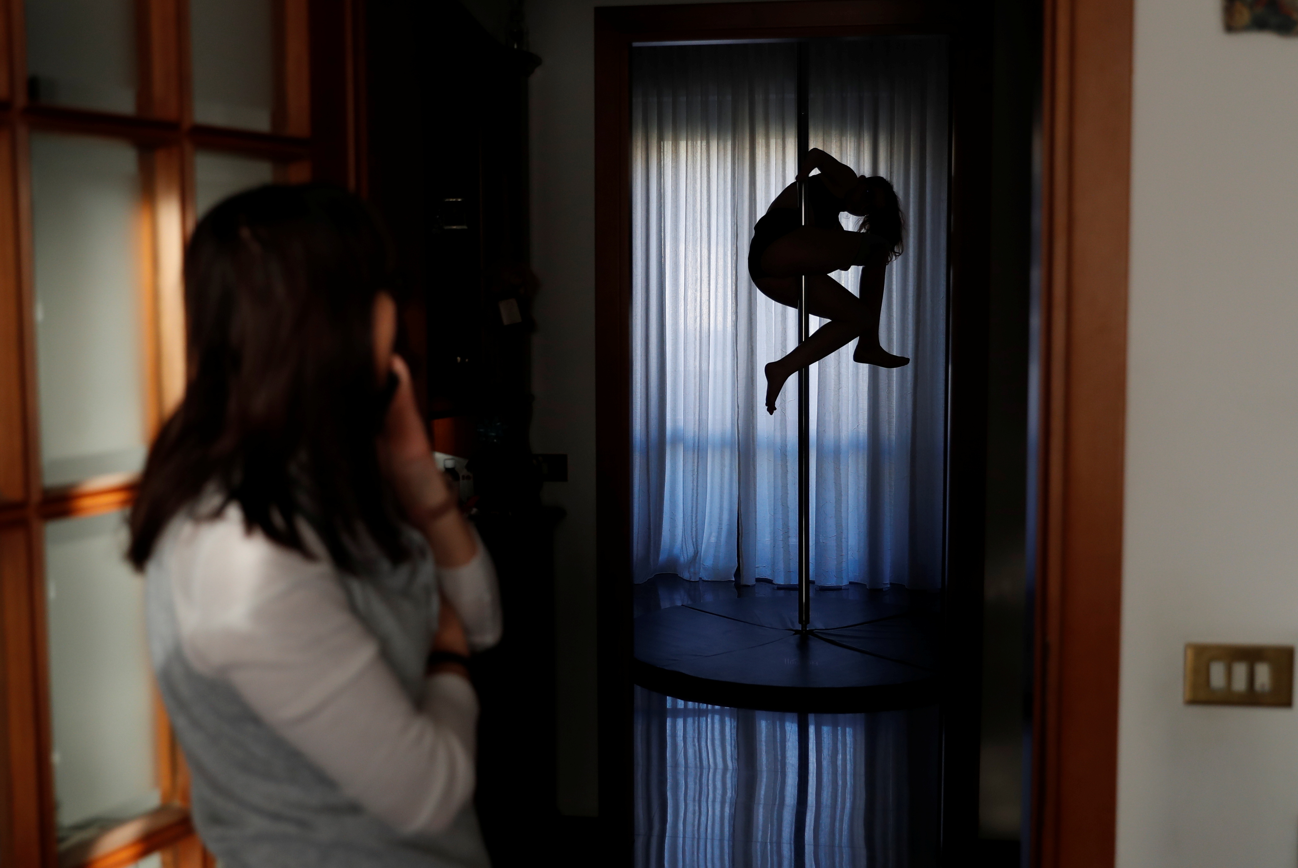 Francesca Cesarini, 15, practices pole dancing at home while her mother Valeria Mencaroni, 47, watches, in Magione, near Perugia, Italy, November 15, 2021. Cesarini was born with no hands and with only one leg so her mother was more than a bit surprised when her daughter told her she wanted to be an acrobatic pole dancer. 
