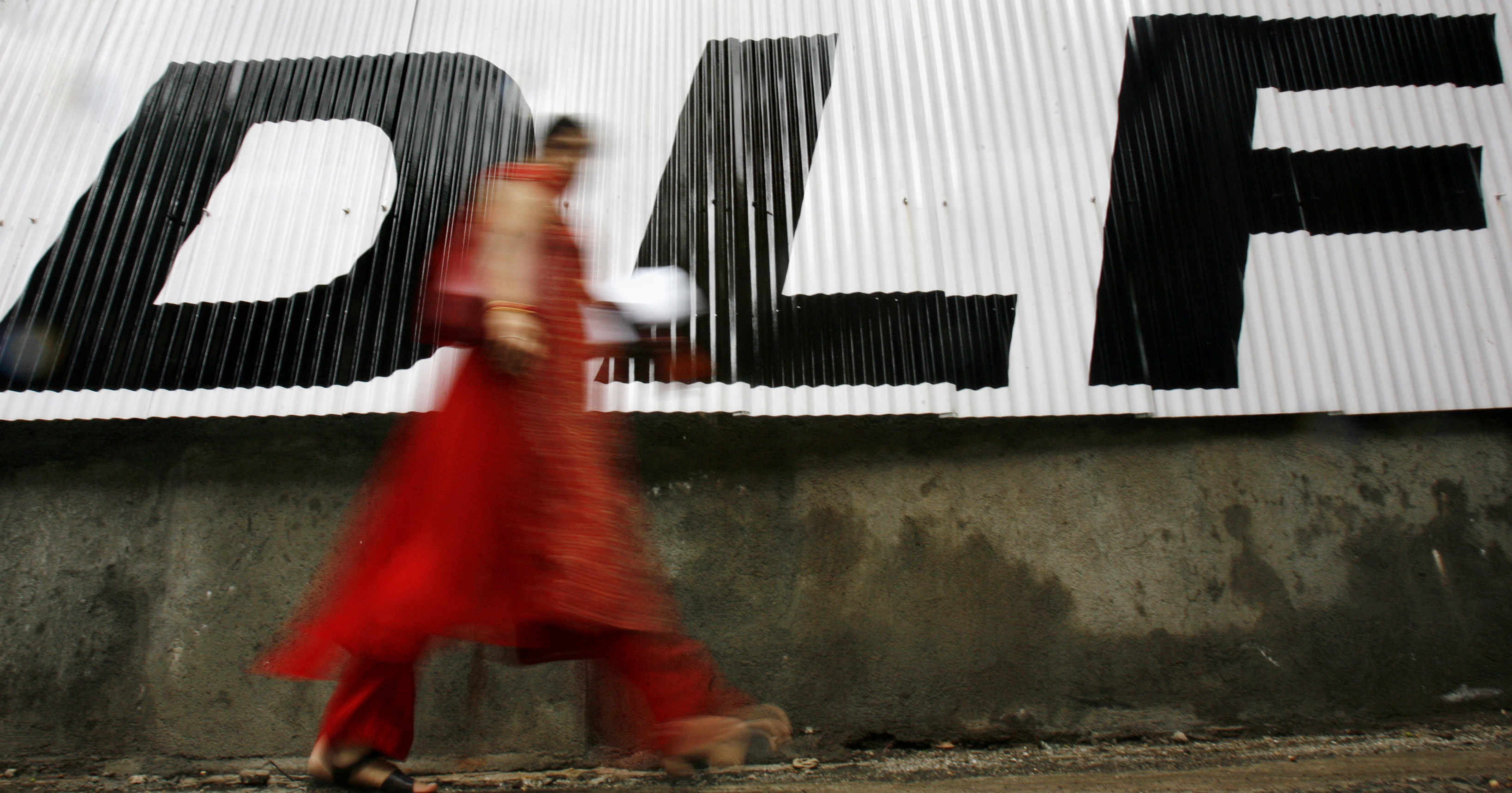 A woman walks past a billboard of Indian property developer DLF Ltd in Mumbai