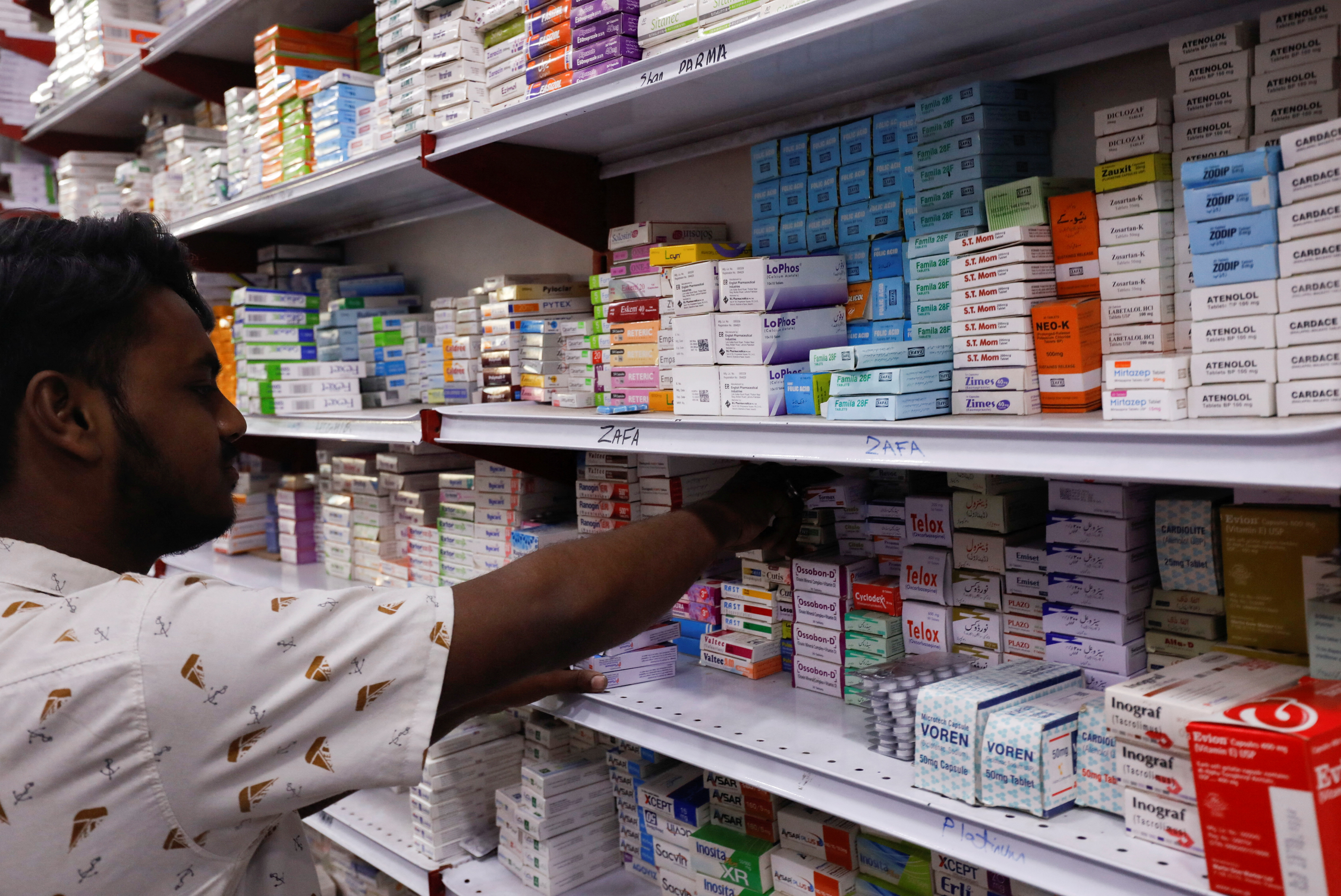 Shopkeeper arranges medicine packs in a medical supply store in Karachi