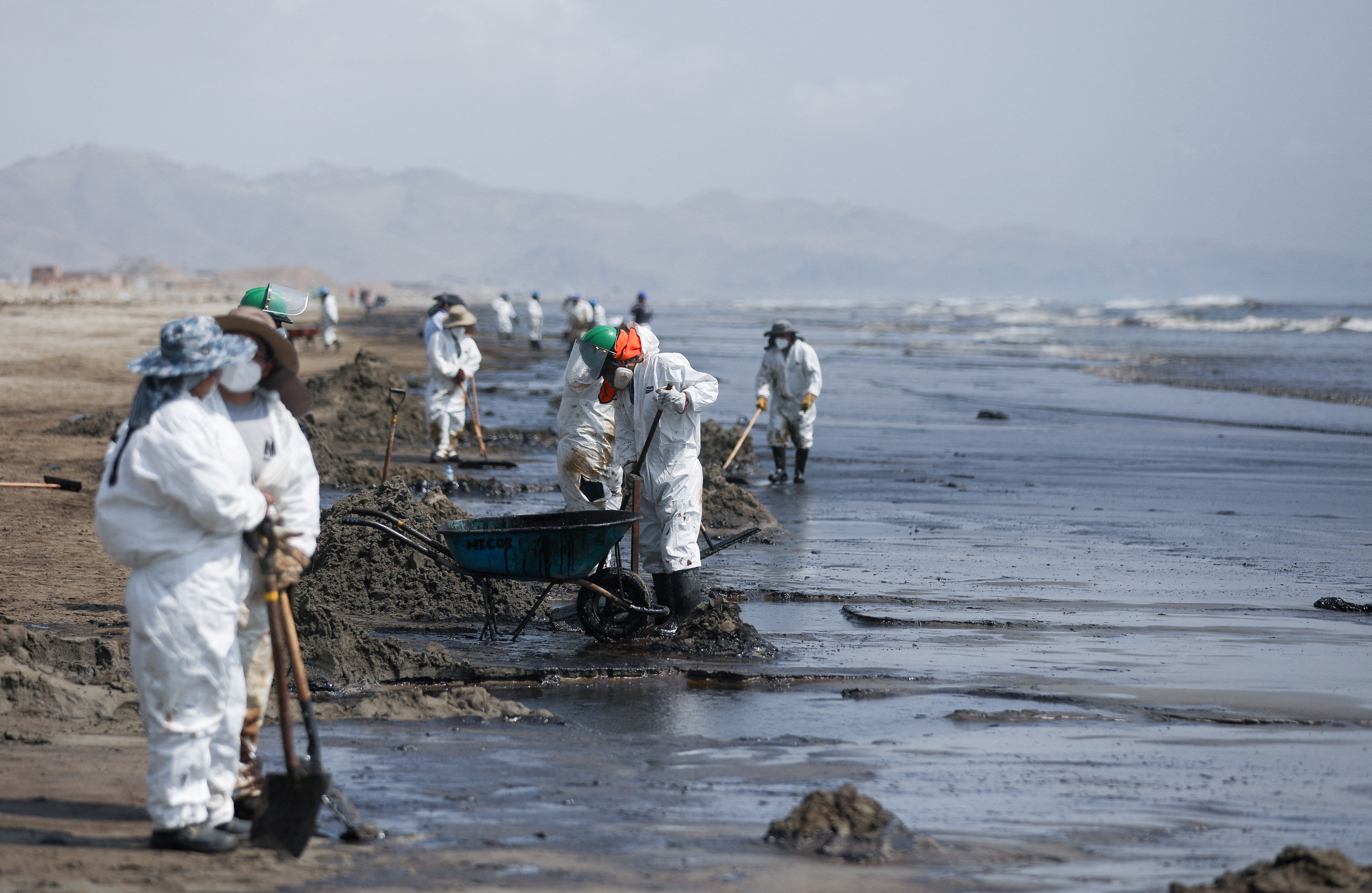 Workers clean up an oil spill in Ventanilla