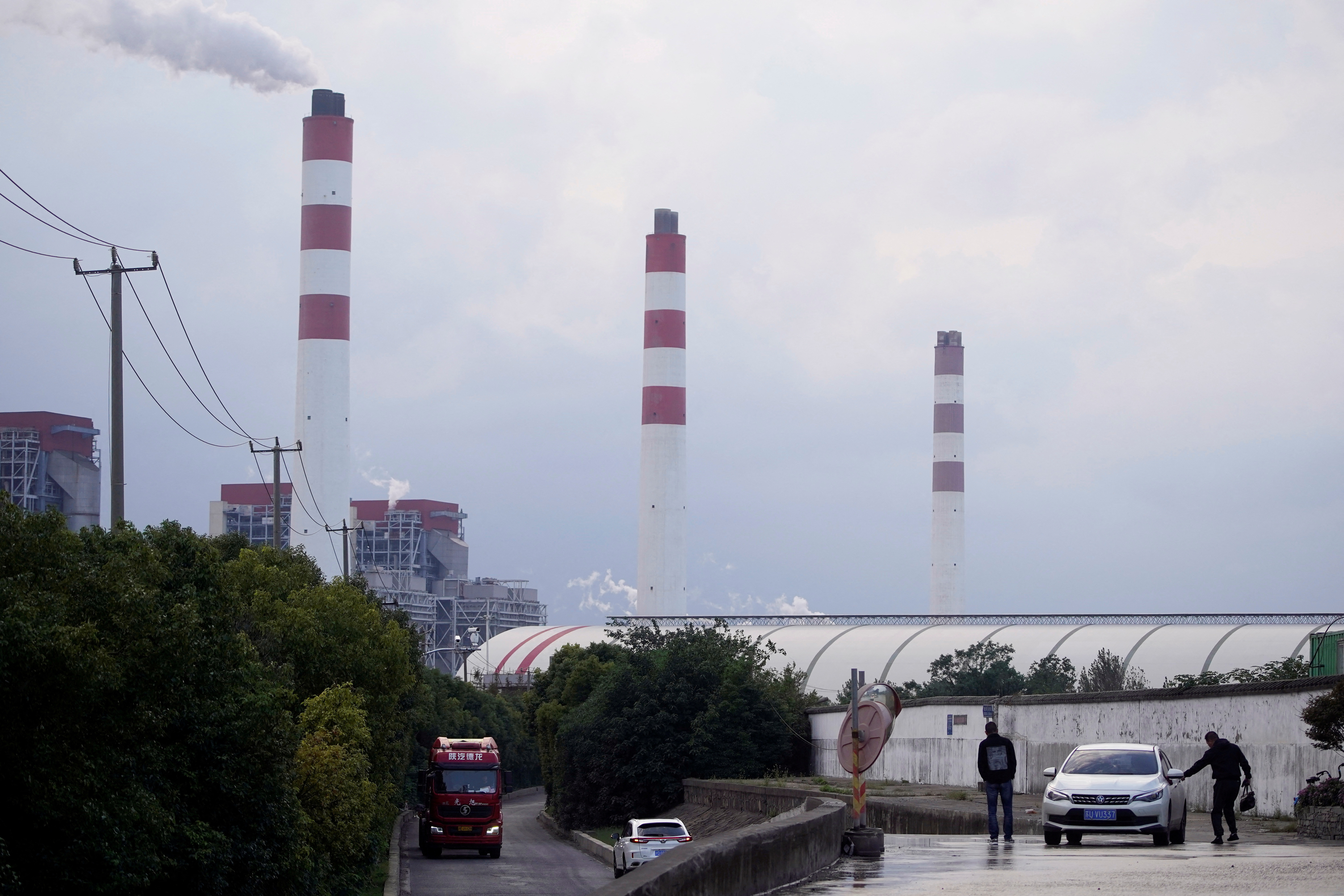 Men stand by a car near a coal-fired power plant in Shanghai