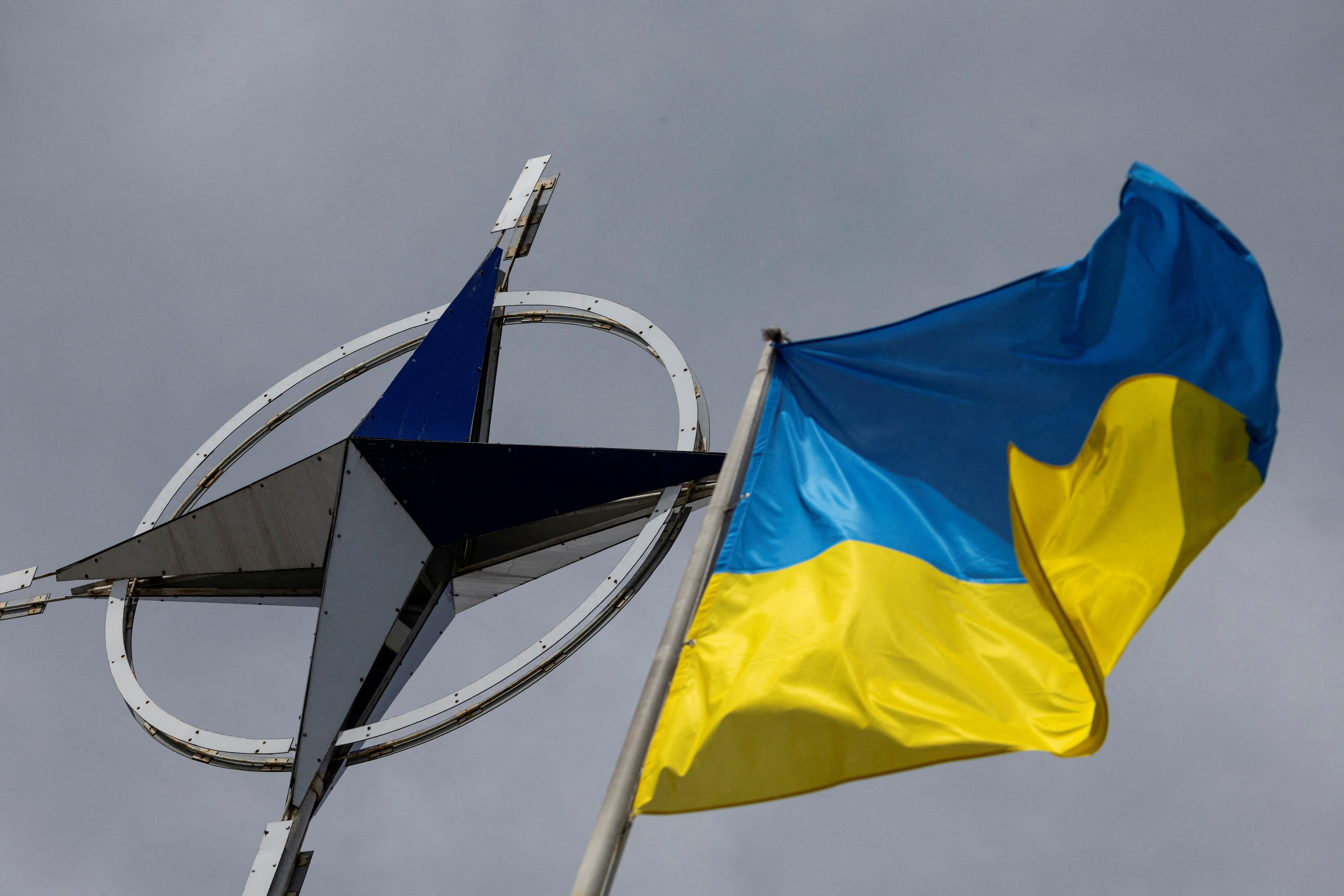 Ukrainian national flag is pictured in front of the NATO emblem in central Kyiv