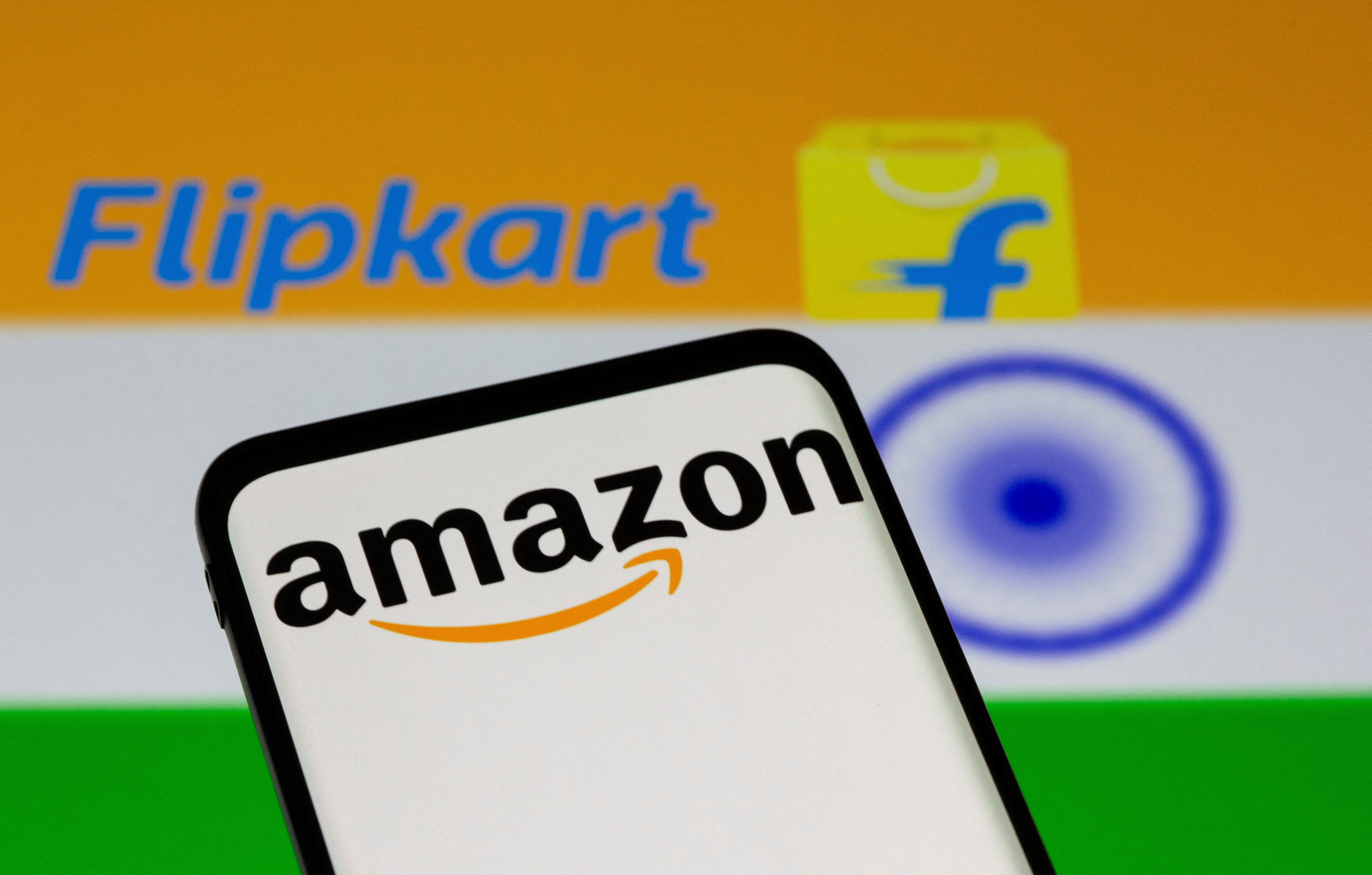 Smartphone with Amazon logo is seen in front of displayed Flipkart logo and Indian flag in this illustration taken