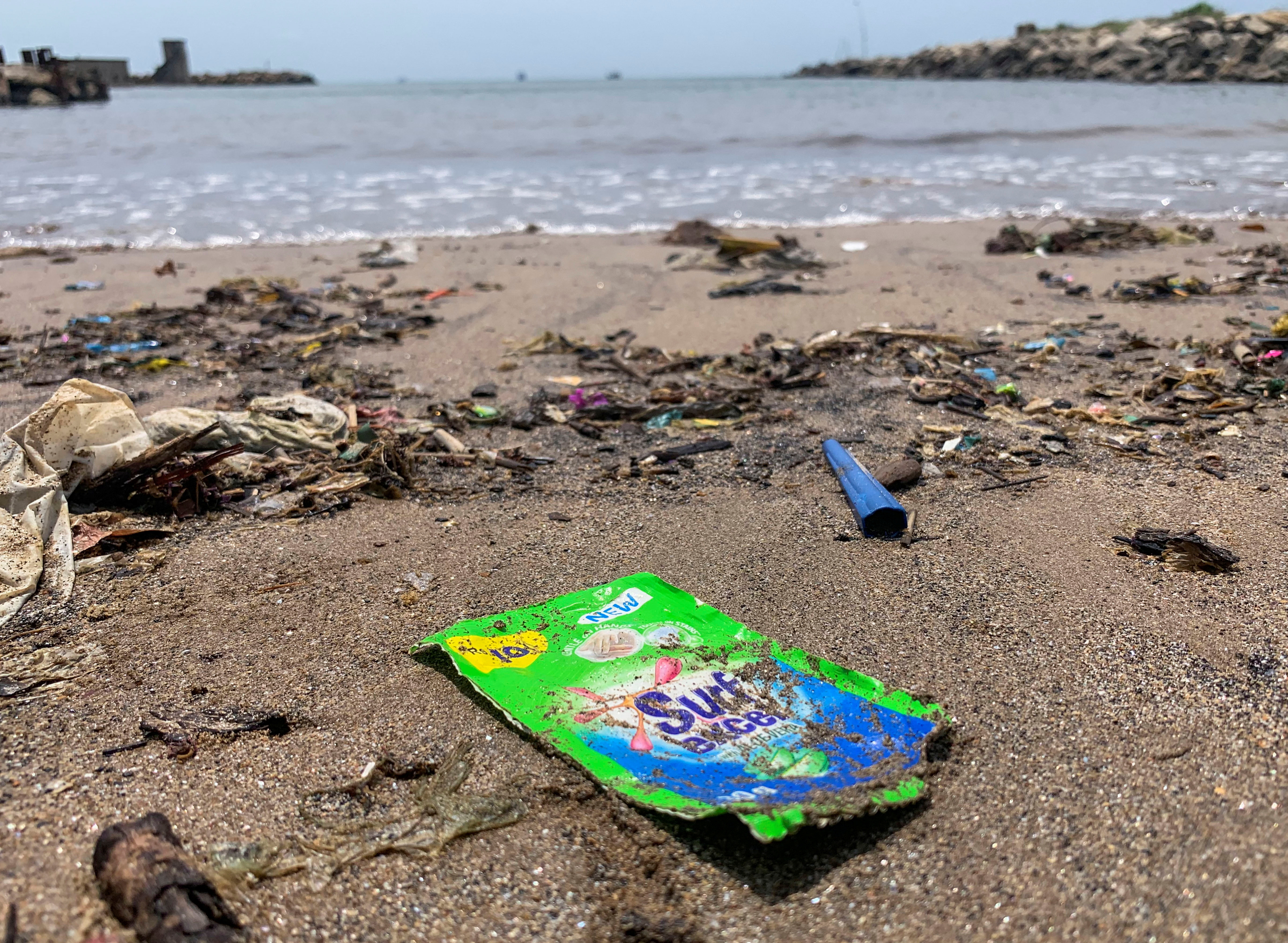 A view of an empty plastic sachet of Unilever's Surf Excel laundry detergent on a beach on Crow Island, Colombo