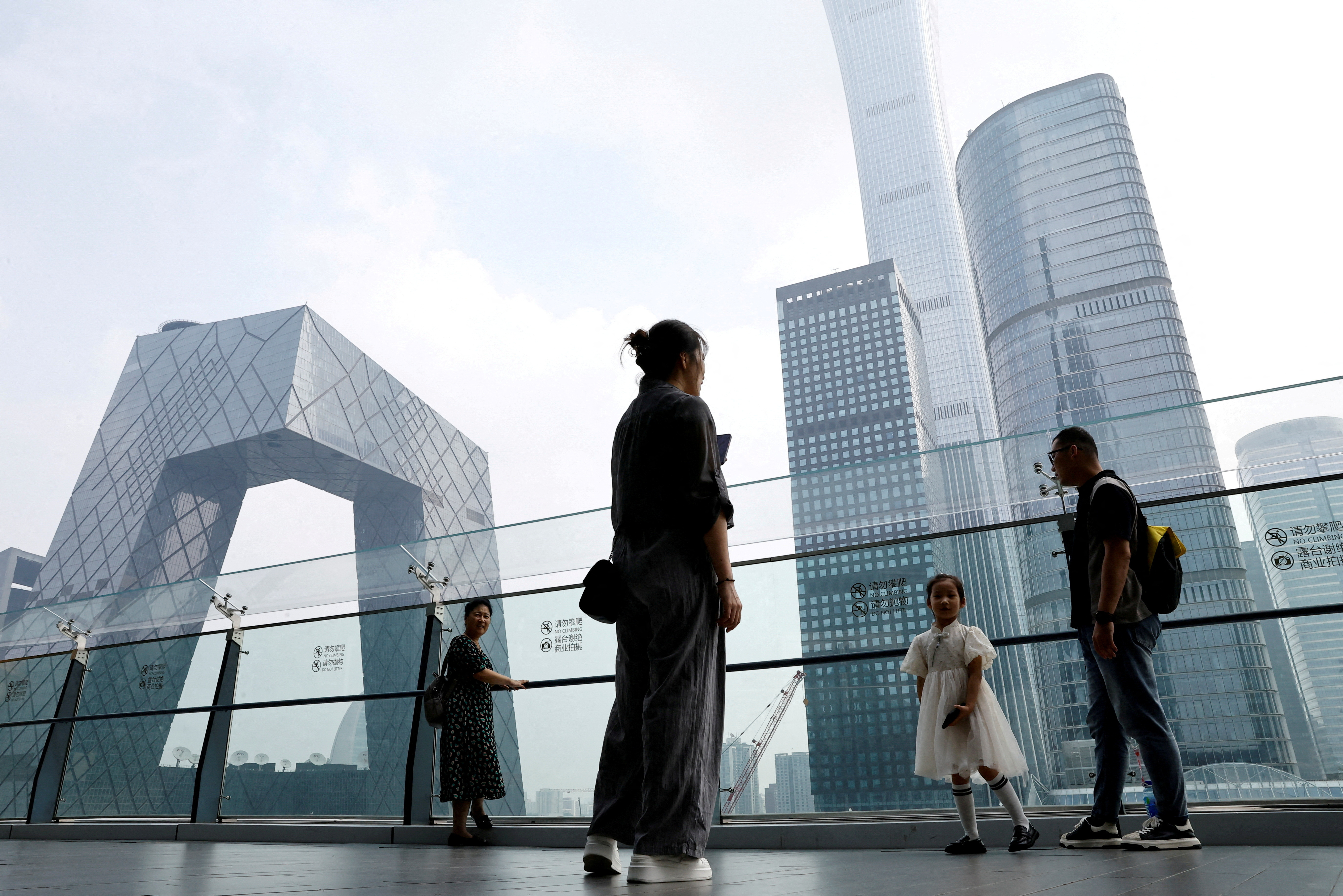 People stand at a shopping mall near the CCTV headquarters and China Zun skyscraper, in Beijing's central business district (CBD)