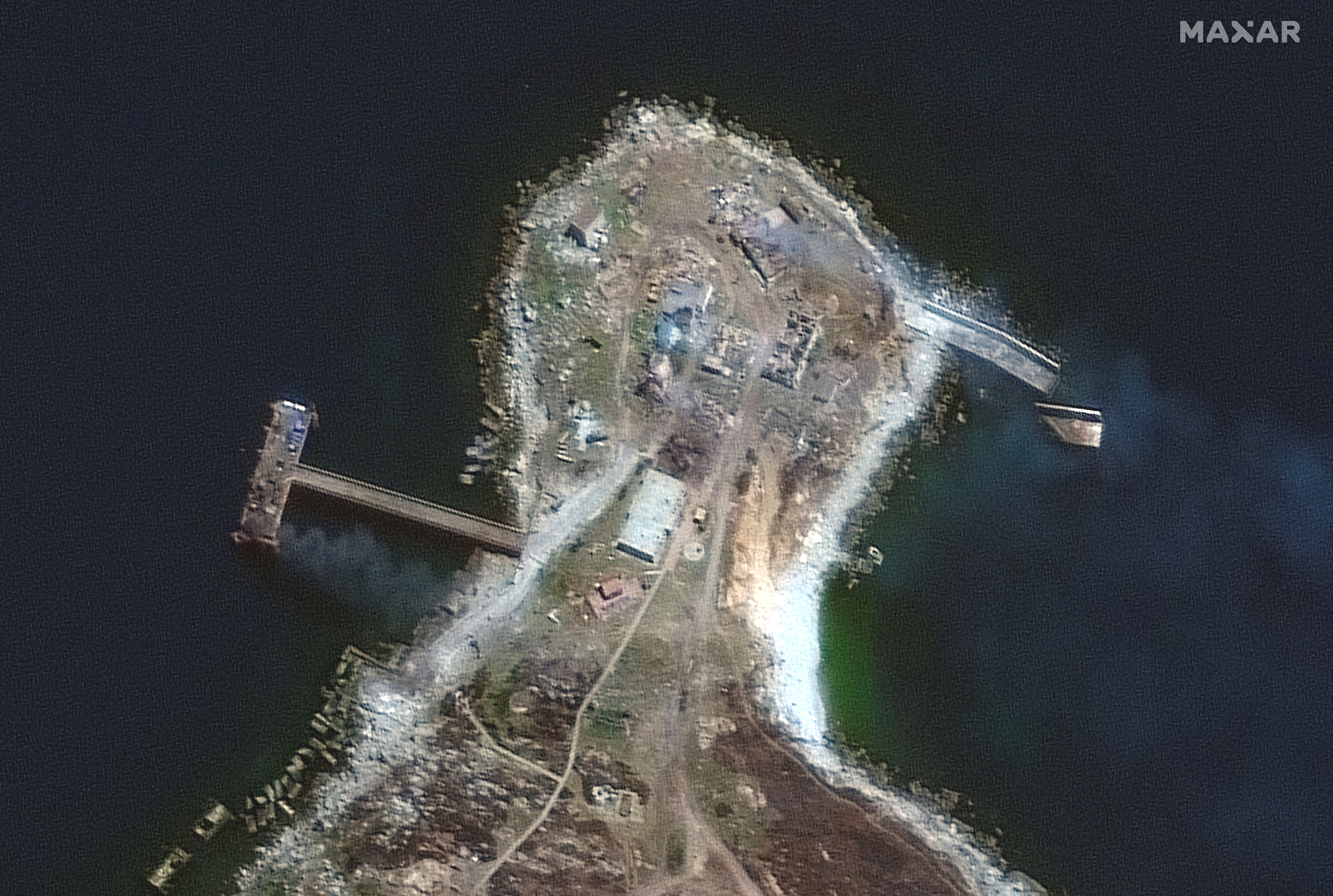 A satellite image shows a burning pier and buildings on the northern end of Snake Island