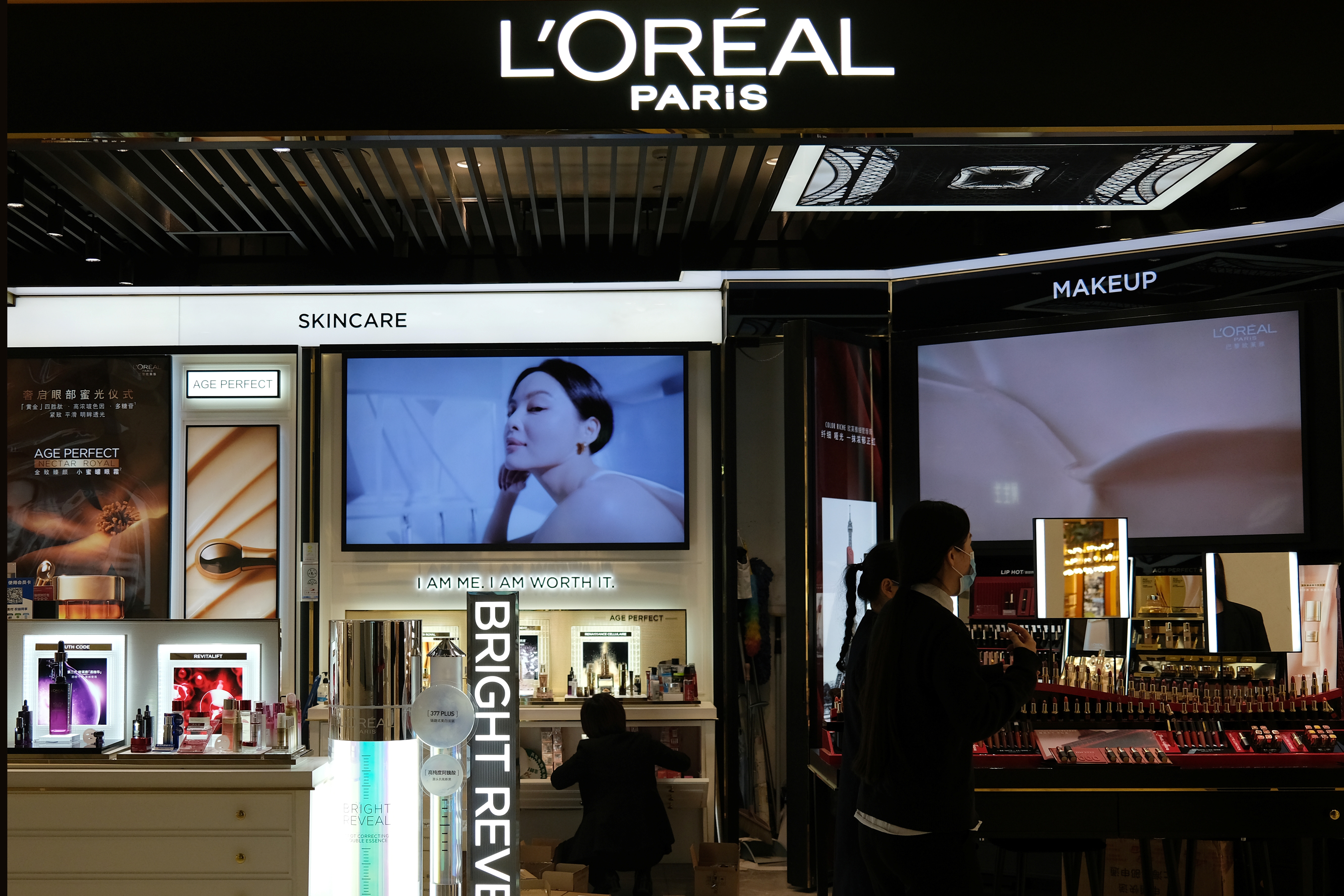 Staff members work at a counter of cosmetics brand L’Oreal at a shopping mall in Beijing