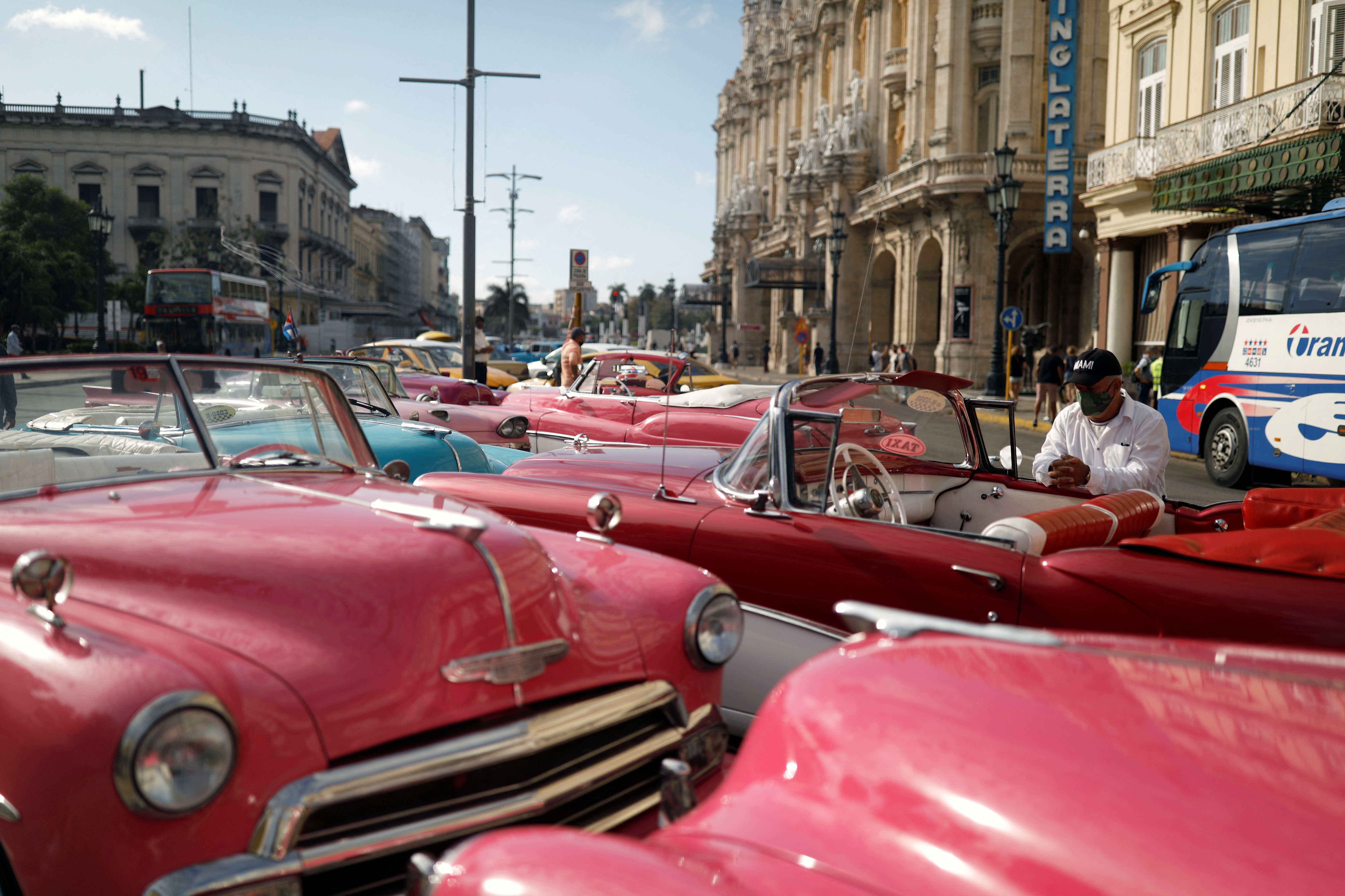 Taxi drivers wait for tourists next to vintage cars in Havana