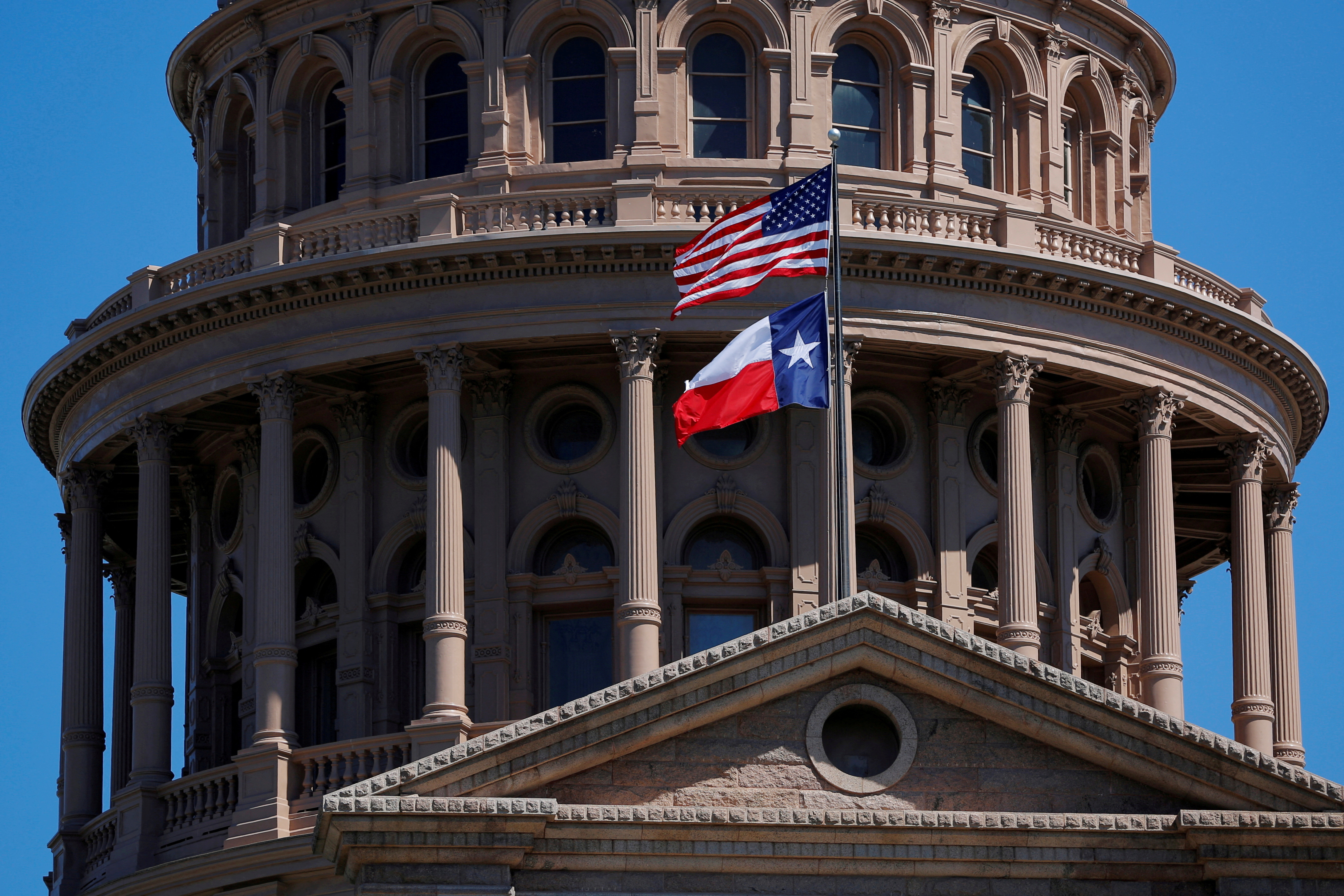 The U.S flag and the Texas State flag fly over the Texas State Capitol in Austin